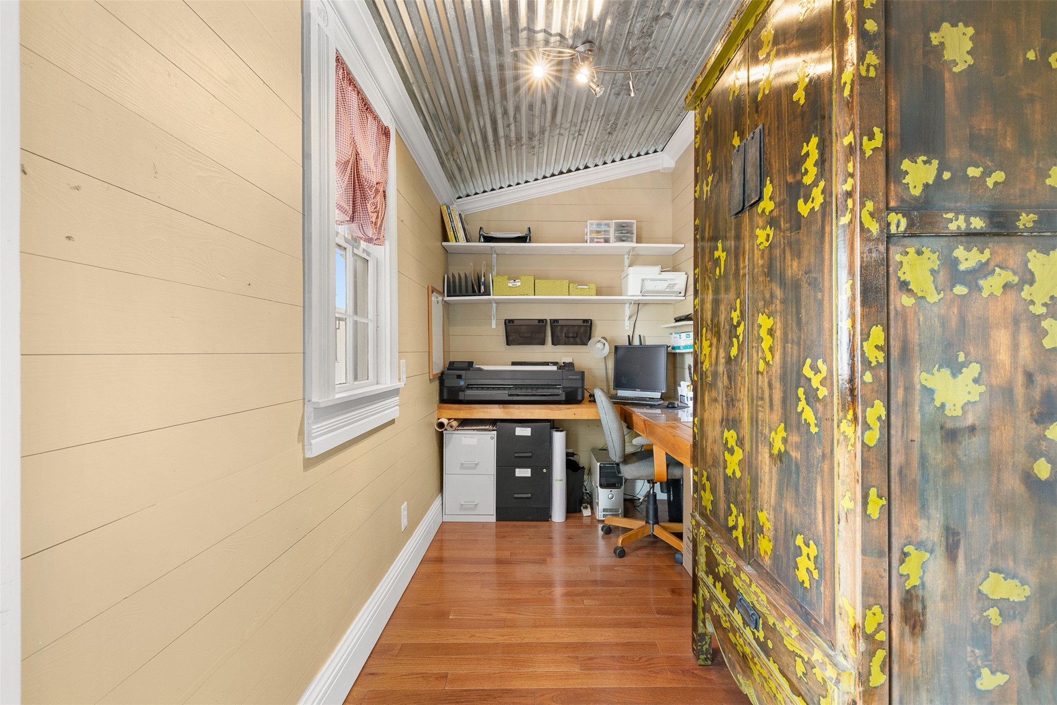 A tucked-away home office makes thoughtful use of space with natural light, wood flooring and open shelving.