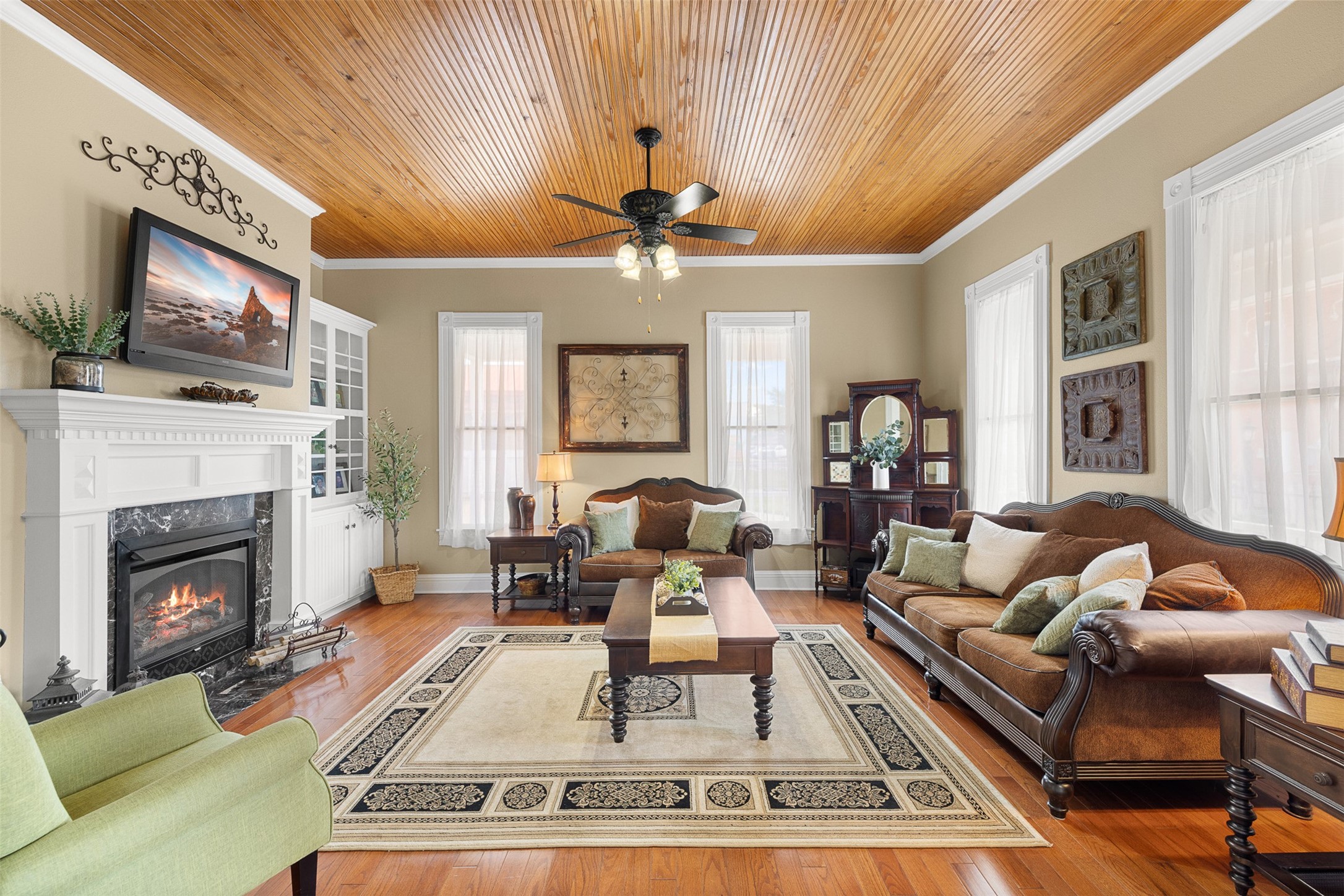 The formal living room pairs soaring ceilings and warm wood floors with a fireplace, built-ins and abundant natural light.