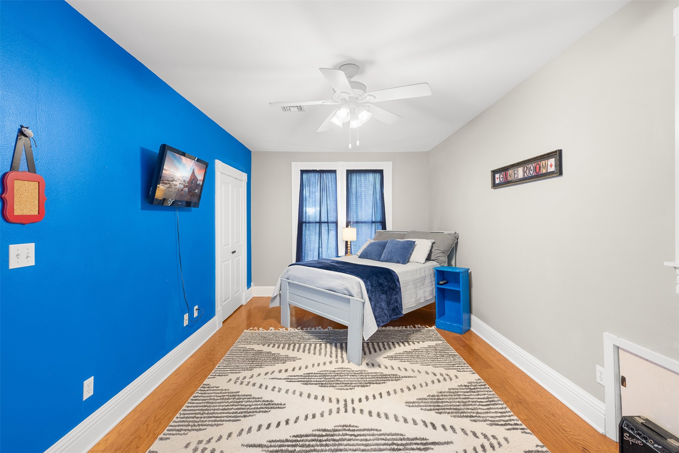 A spacious secondary bedroom offers wood floors, high ceilings and plenty of flexibility for family or guests.
