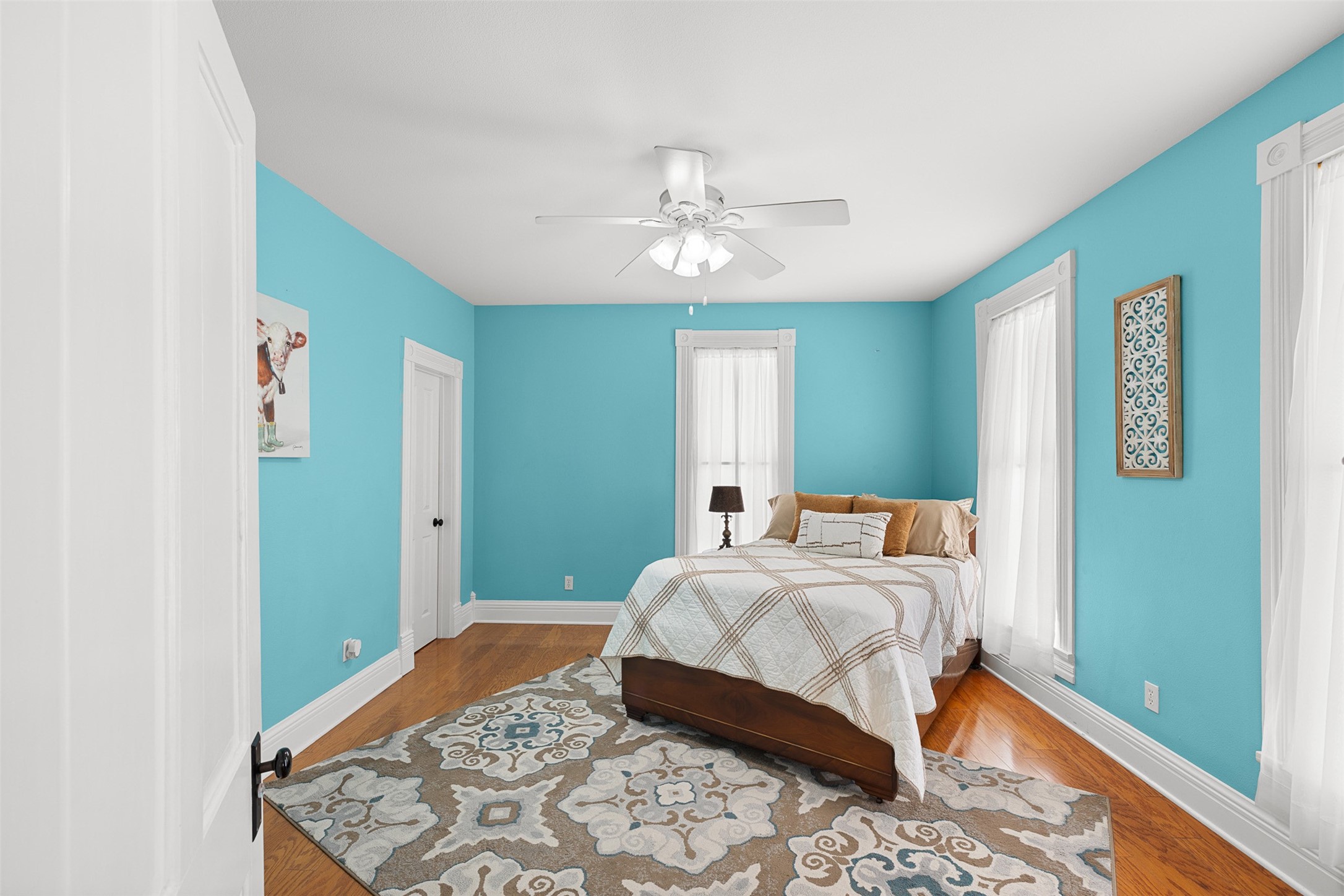 This cheerful upstairs bedroom features wood flooring, high ceilings and lovely natural light.