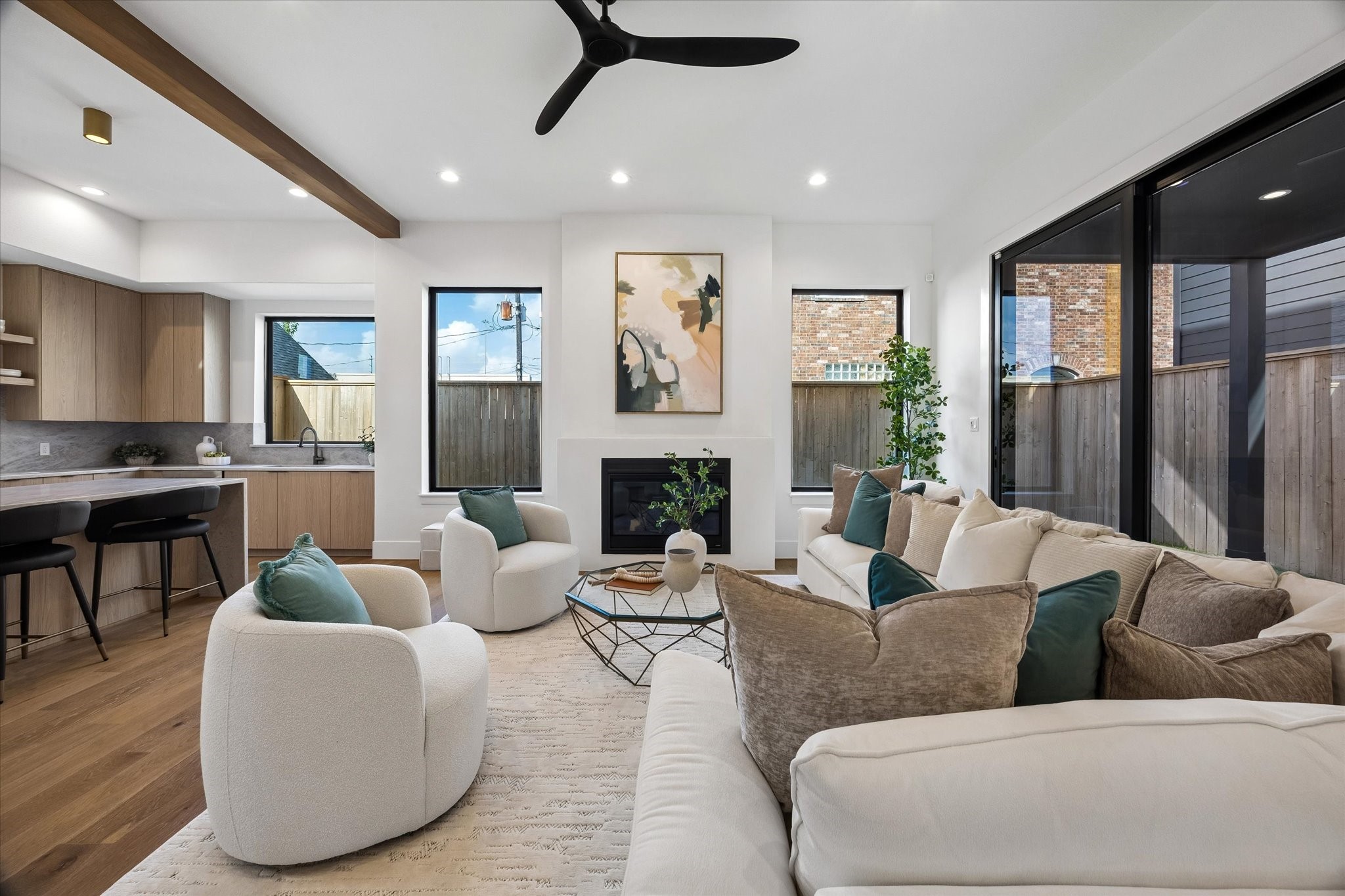 Framed by tall windows, the fireplace anchors the living room while expansive glass doors bring the covered outdoor space directly into view. Its generous proportions leave plenty of room for conversation, entertaining and everyday gathering.