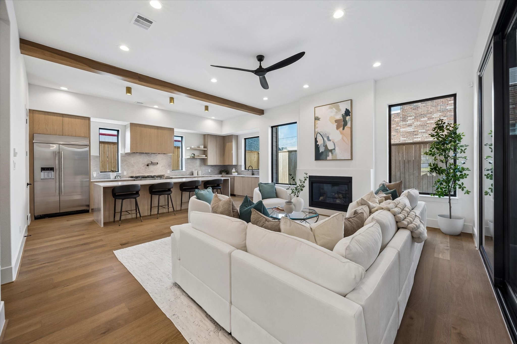 From this angle, the connection between the living room and kitchen takes center stage, with the oversized island creating a natural gathering point between the two. A warm wood ceiling beam subtly defines the kitchen while preserving the openness of the space.