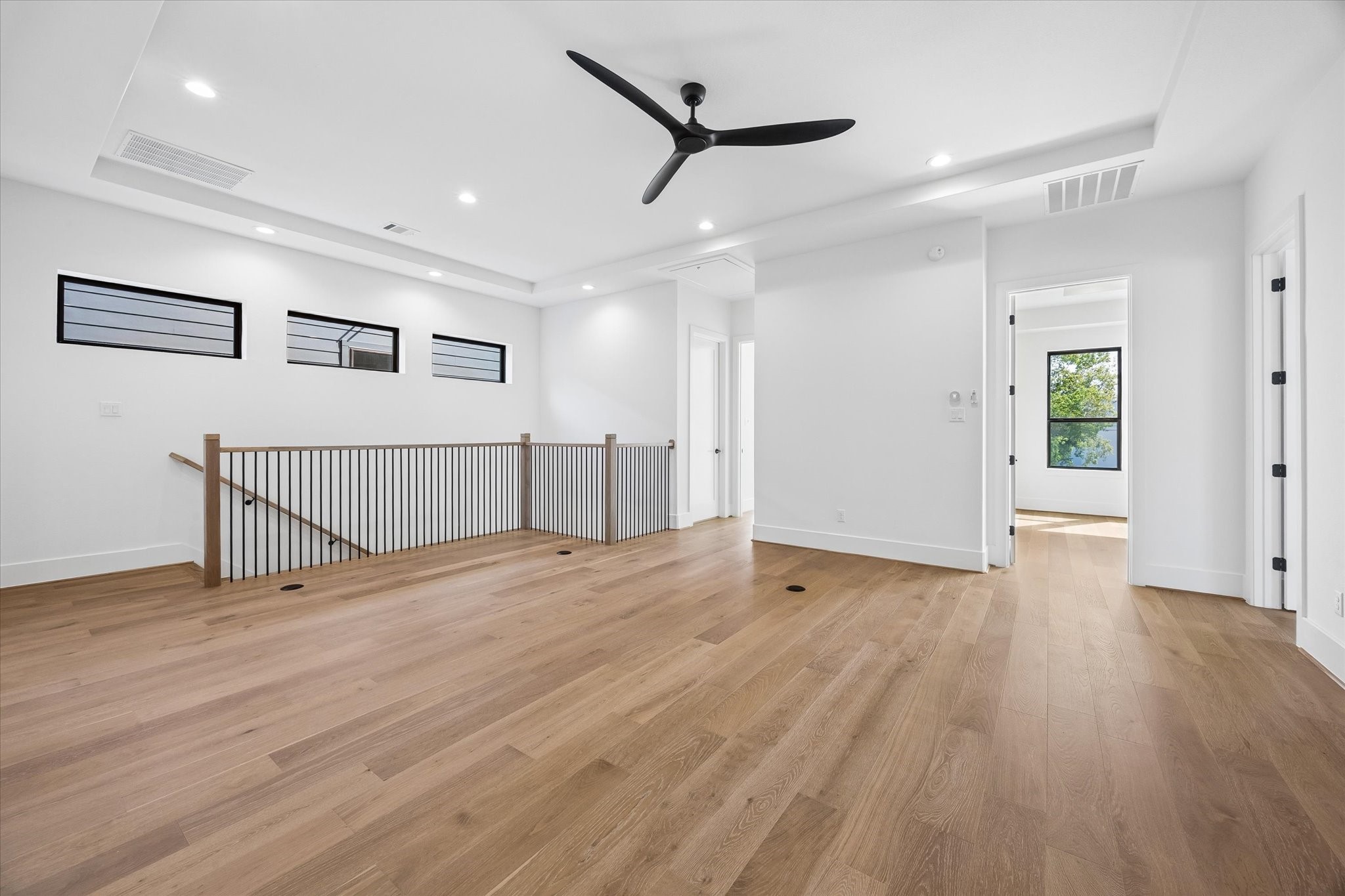 Another view of the upstairs highlights its generous scale, tray ceiling and continuation of hardwood flooring. High set windows bring in natural light while maintaining privacy.