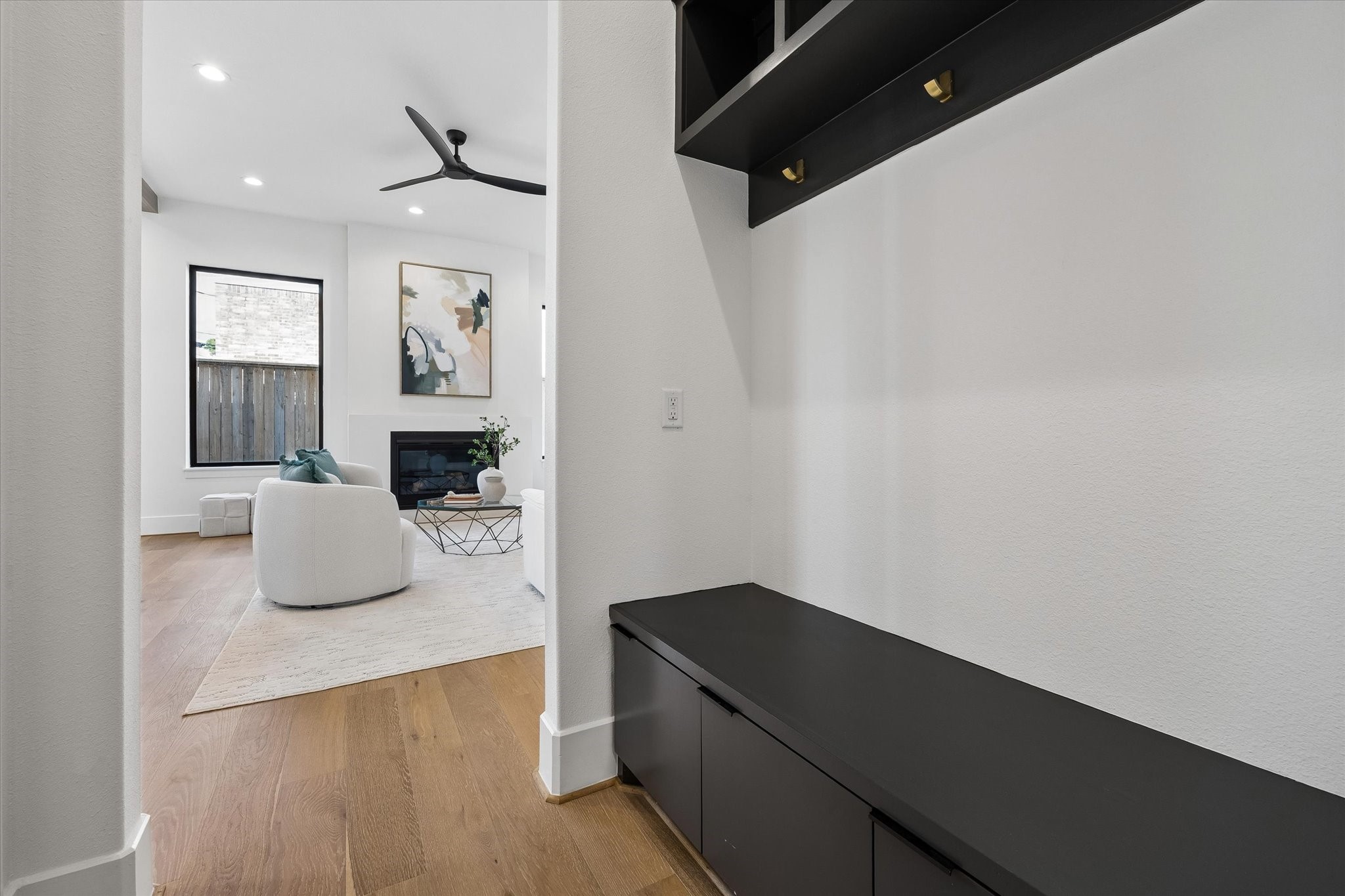 Built in mudroom storage creates a polished drop zone just off the main living spaces, pairing a bench with concealed cabinetry, overhead cubbies and brass hooks for everyday organization.