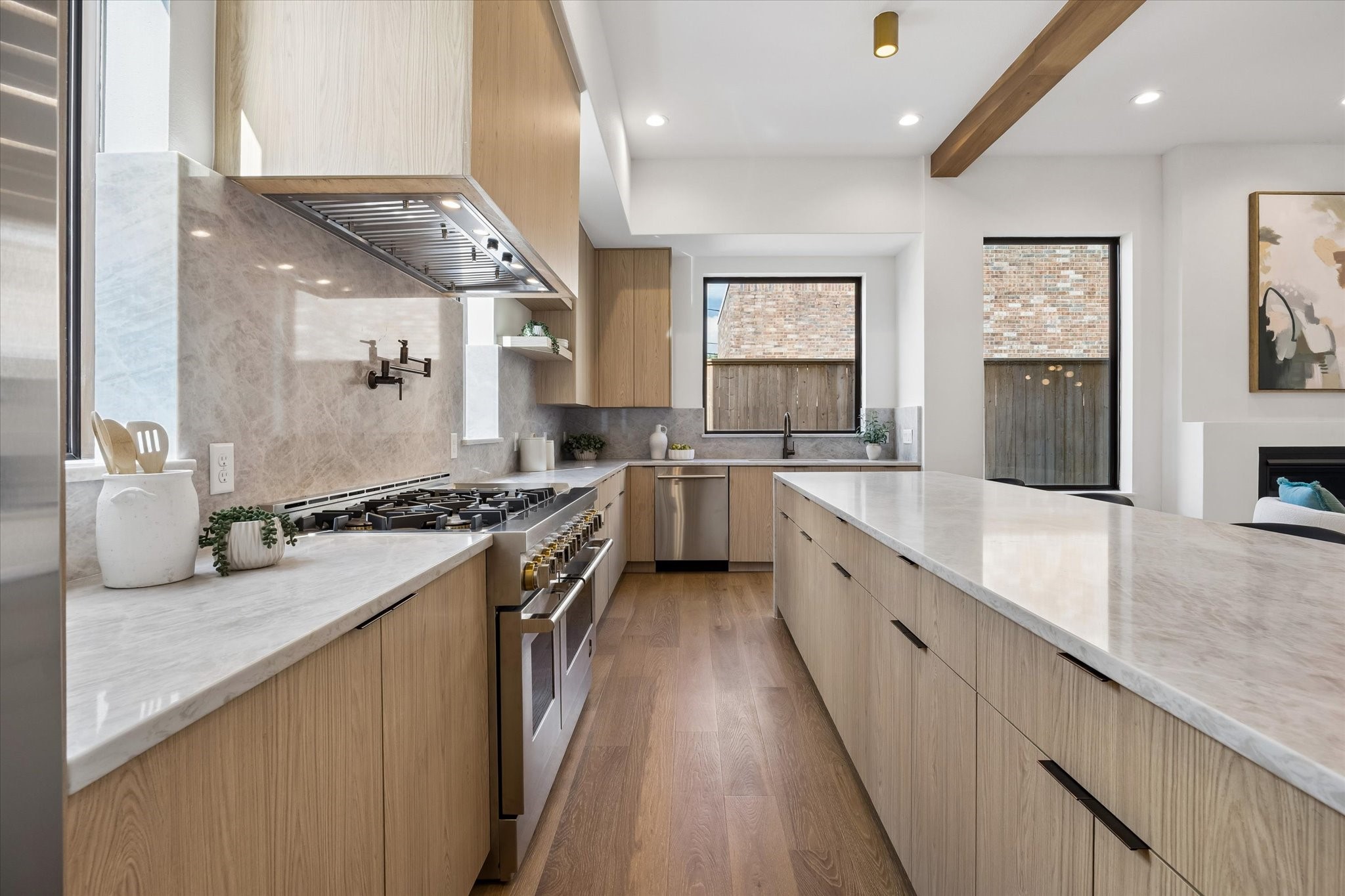 Serious cooking space comes into focus with a professional style gas range, substantial vent hood and convenient pot filler framed by stone. Long stretches of counter space and island storage provide plenty of room for prep without sacrificing the streamlined design.