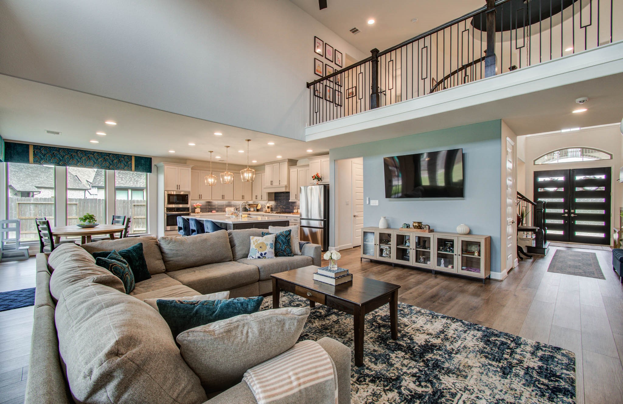 Experience open-concept living with a spacious living room featuring an eye-level TV mount, seamlessly flowing into a modern kitchen and dining area, perfect for entertaining and relaxation.