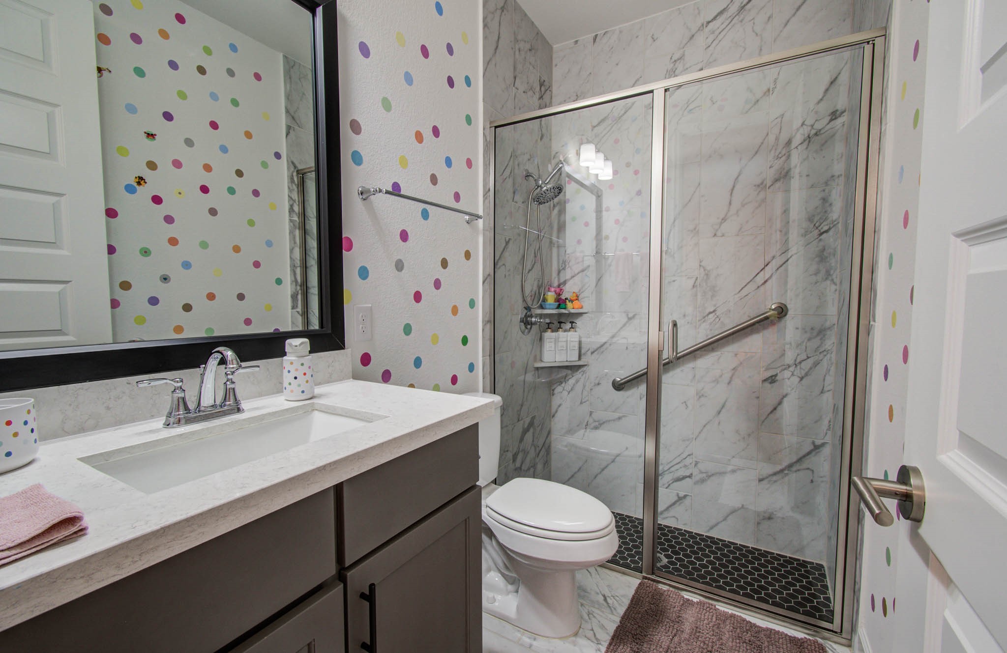 Bright and cheerful, this secondary bathroom boasts a stylish glass-enclosed shower with elegant marble tiles, perfect for guests or family members.