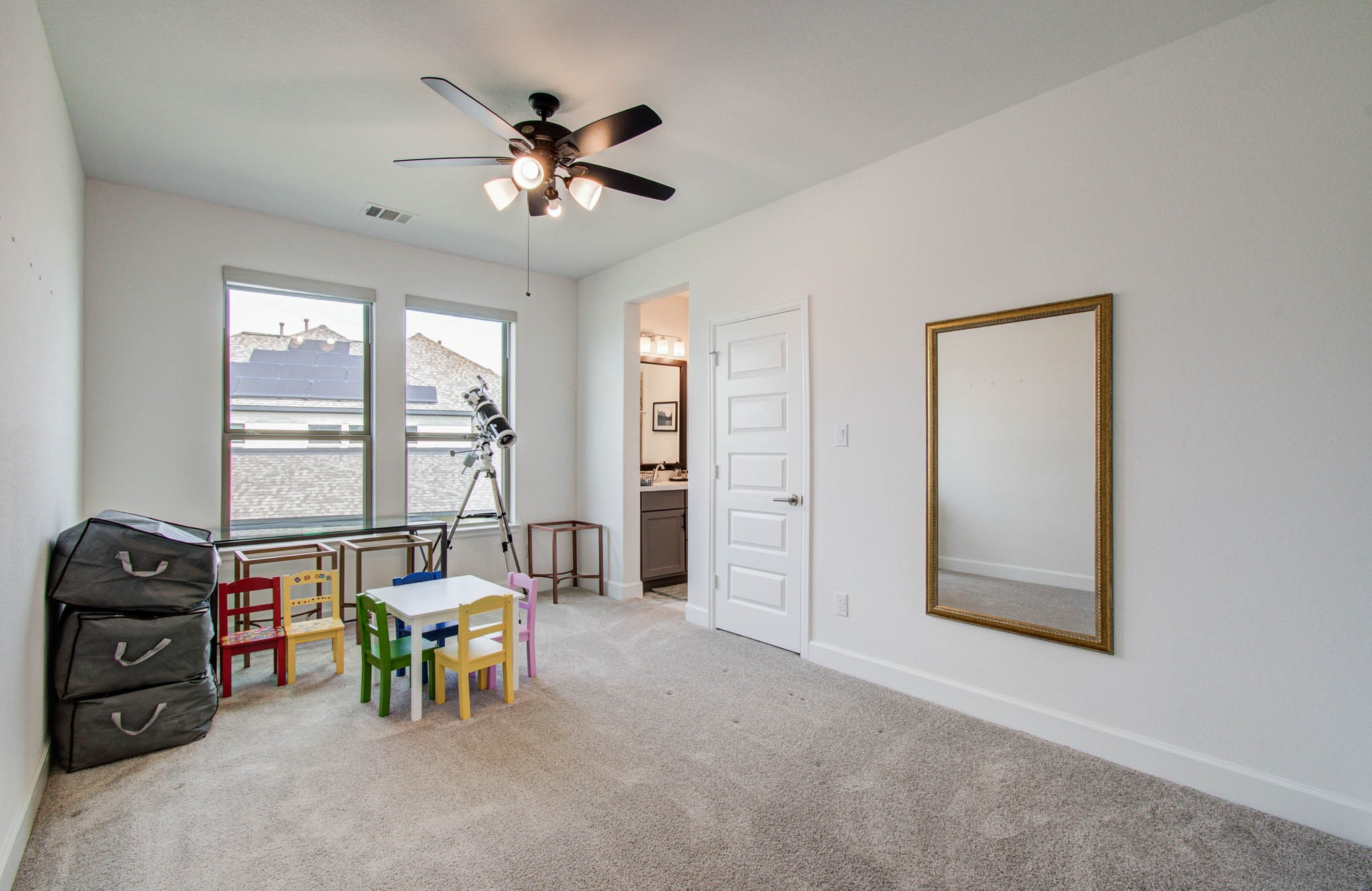 secondary bedroom with roller shades, ceiling fan and jack and jill bath.