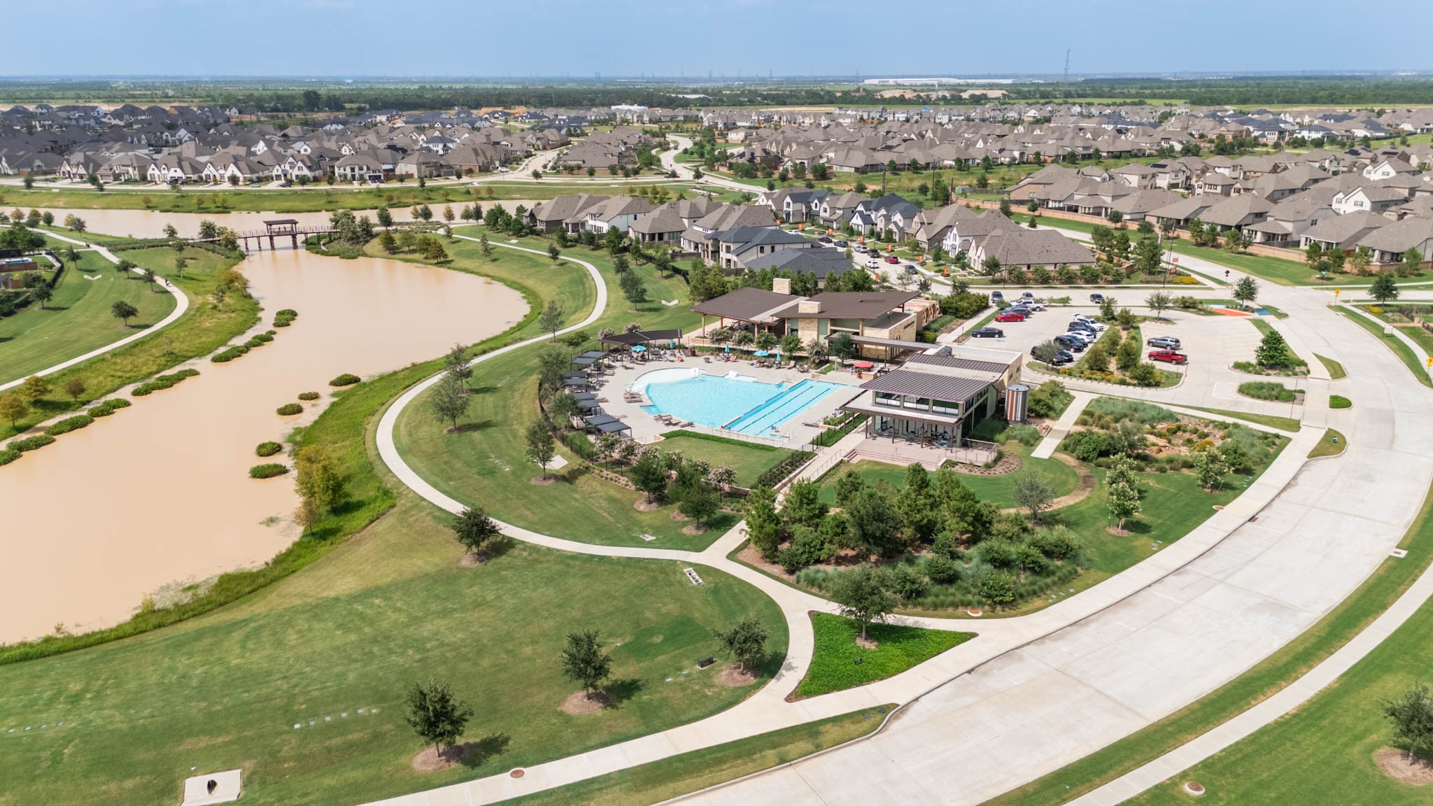 Experience modern suburban living in this serene, family-friendly community featuring a central recreational area with a large swimming pool, inviting clubhouse, and a scenic pond surrounded by lush, landscaped greenery.