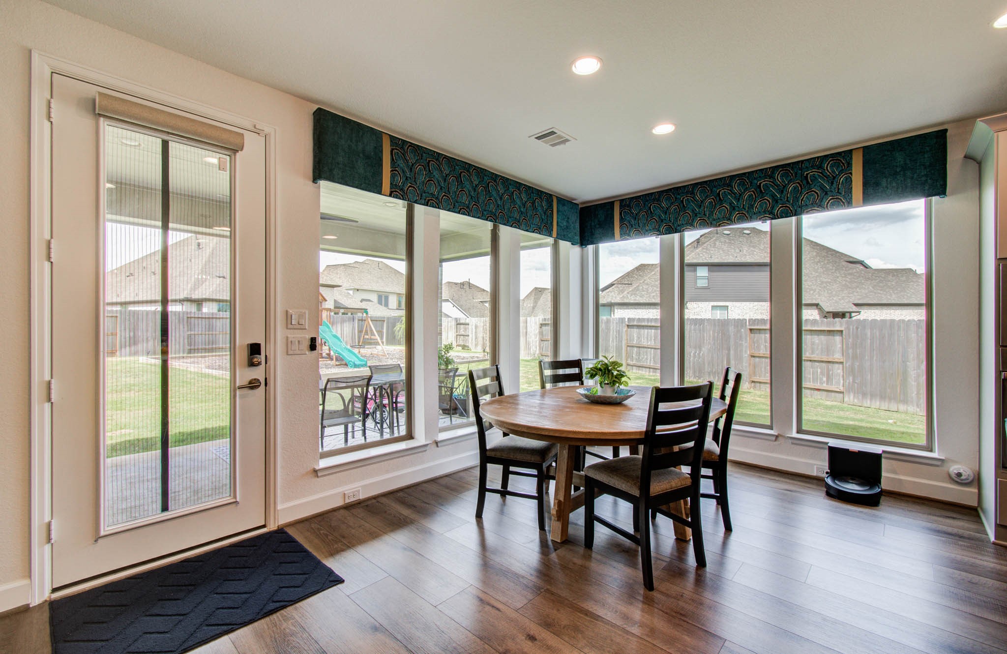 Sunlit dining area with expansive windows framing a delightful backyard view.