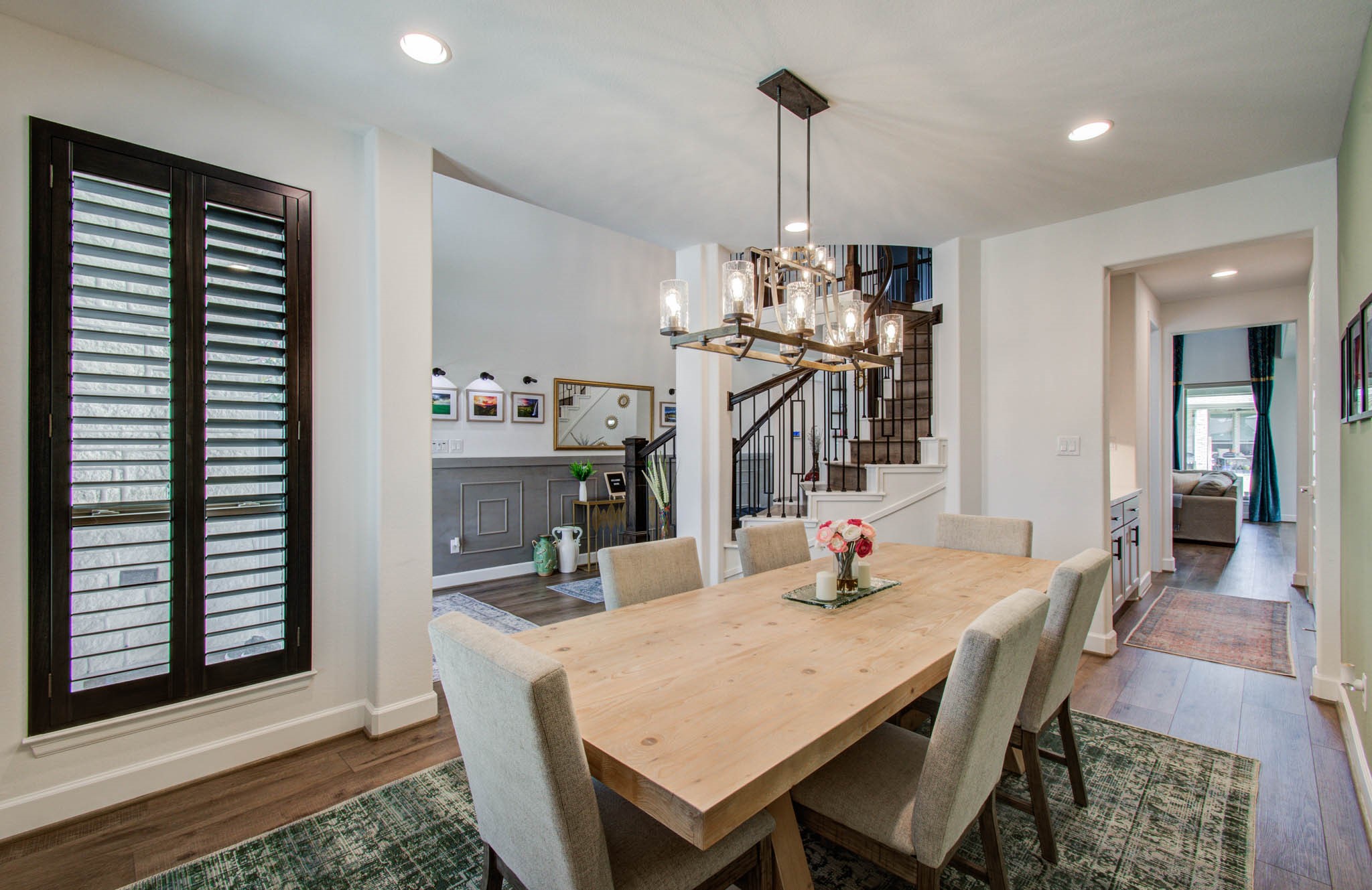 Elegant custom shutters grace the front of this inviting home, complementing the open dining area and stylish staircase for a perfect blend of charm and sophistication.
