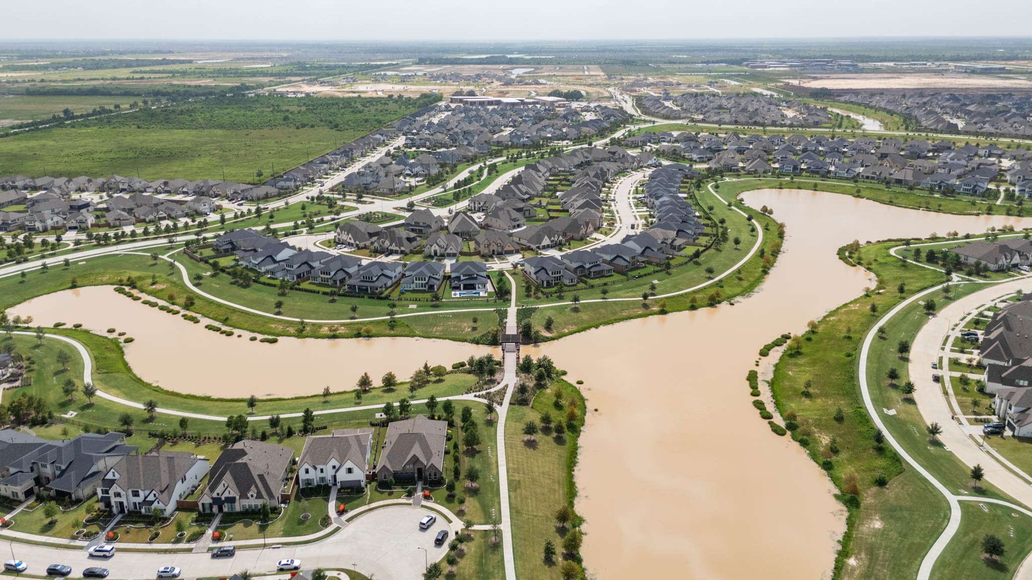 Experience stunning aerial views of a beautifully designed community with winding streets, lush greenery, and serene waterways, offering a perfect blend of natural beauty and modern living.