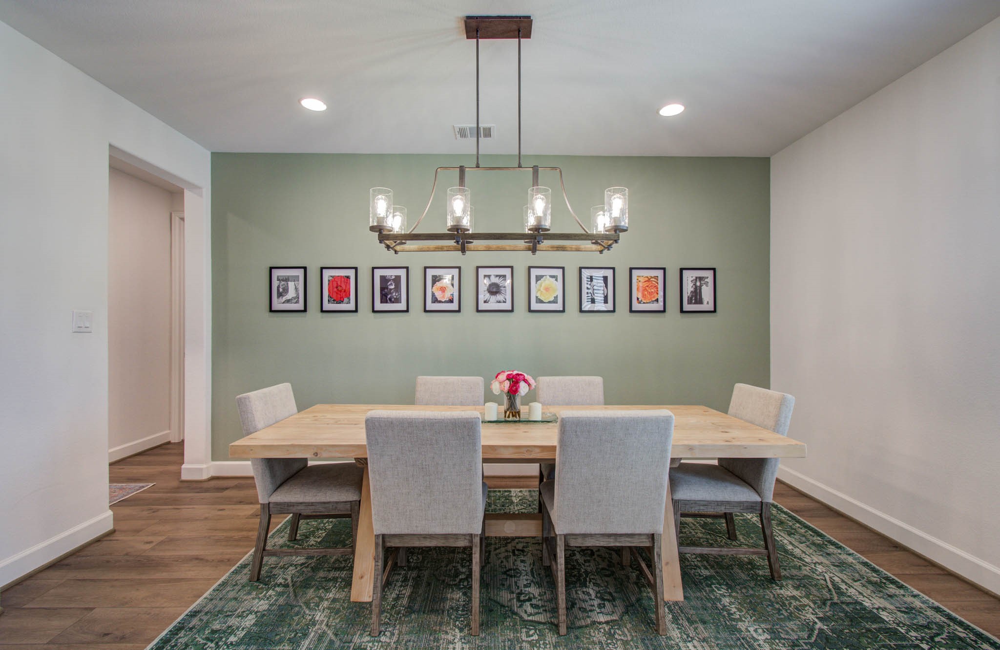 Bright and inviting, this dining room boasts a modern chandelier complemented by recessed lighting, creating a stylish and welcoming atmosphere.