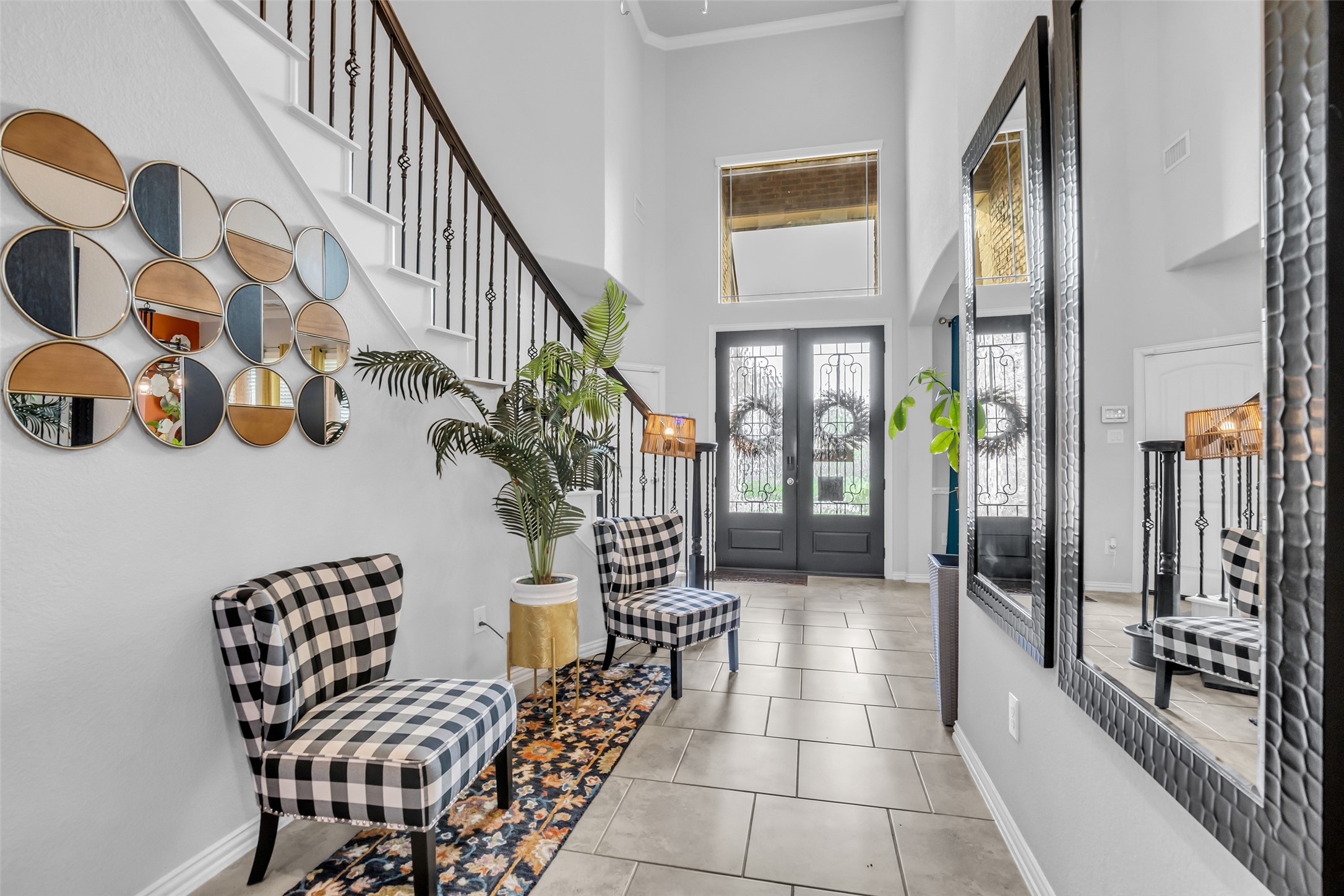 This elegant entryway features high ceilings, a staircase with decorative railing creating a welcoming and sophisticated entry ambiance.