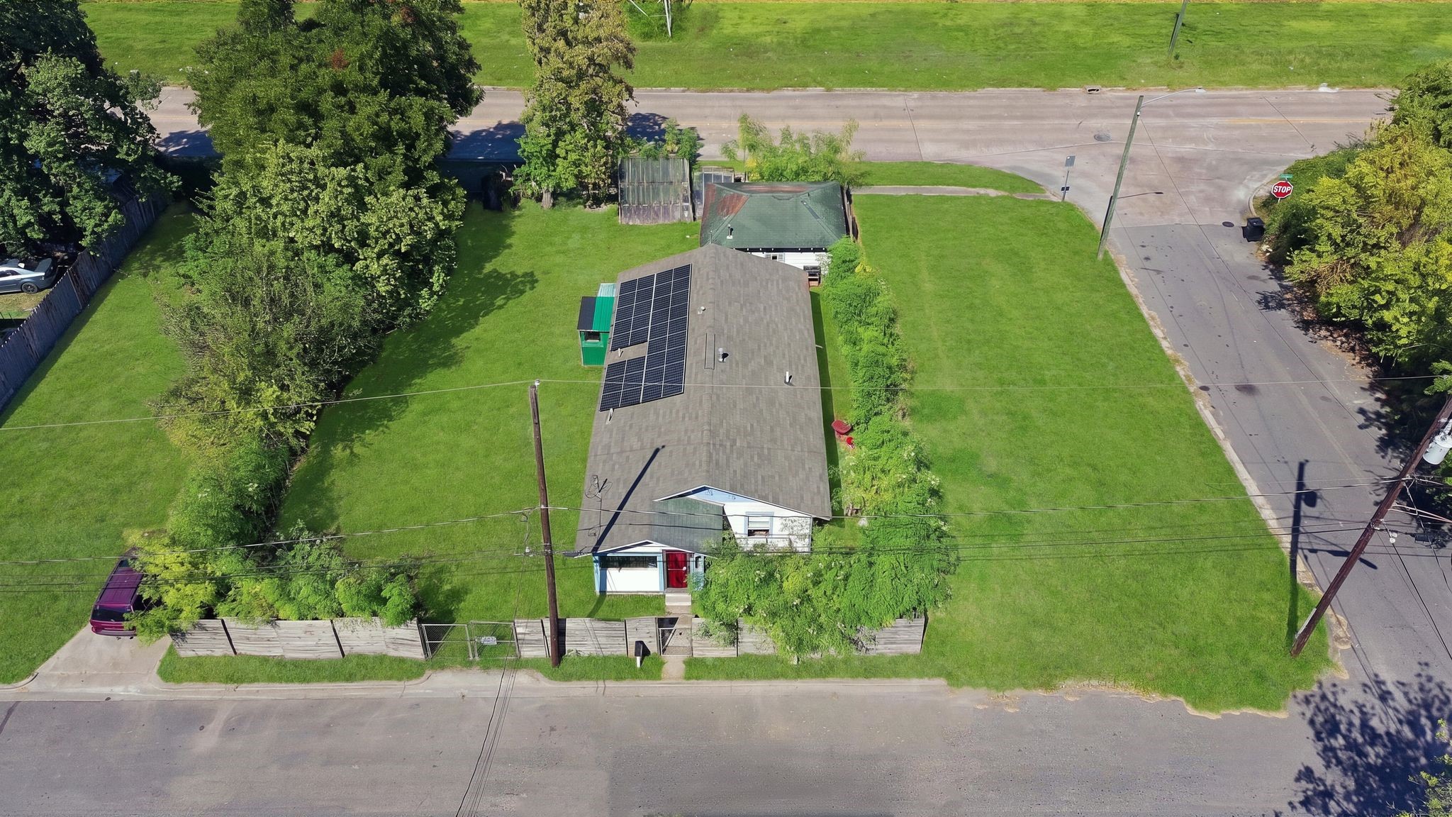 Aerial view of the property showing the fenced front yard and ample green space.