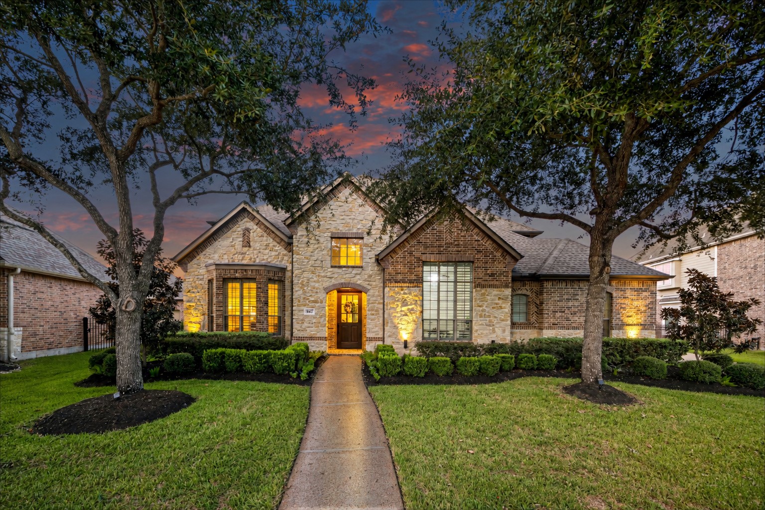 Grand front approach leading to the arched entry, framed by mature oaks.