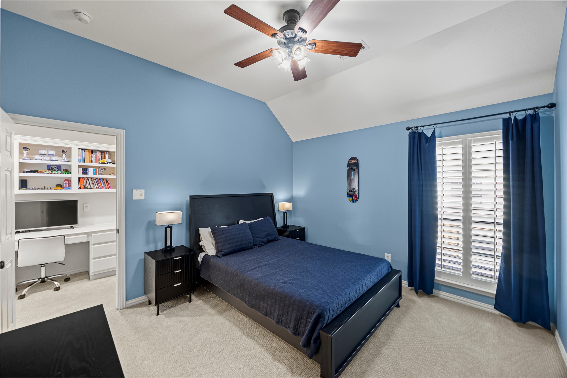 Bedroom with custom built-in shelving, ceiling fan, and natural light.