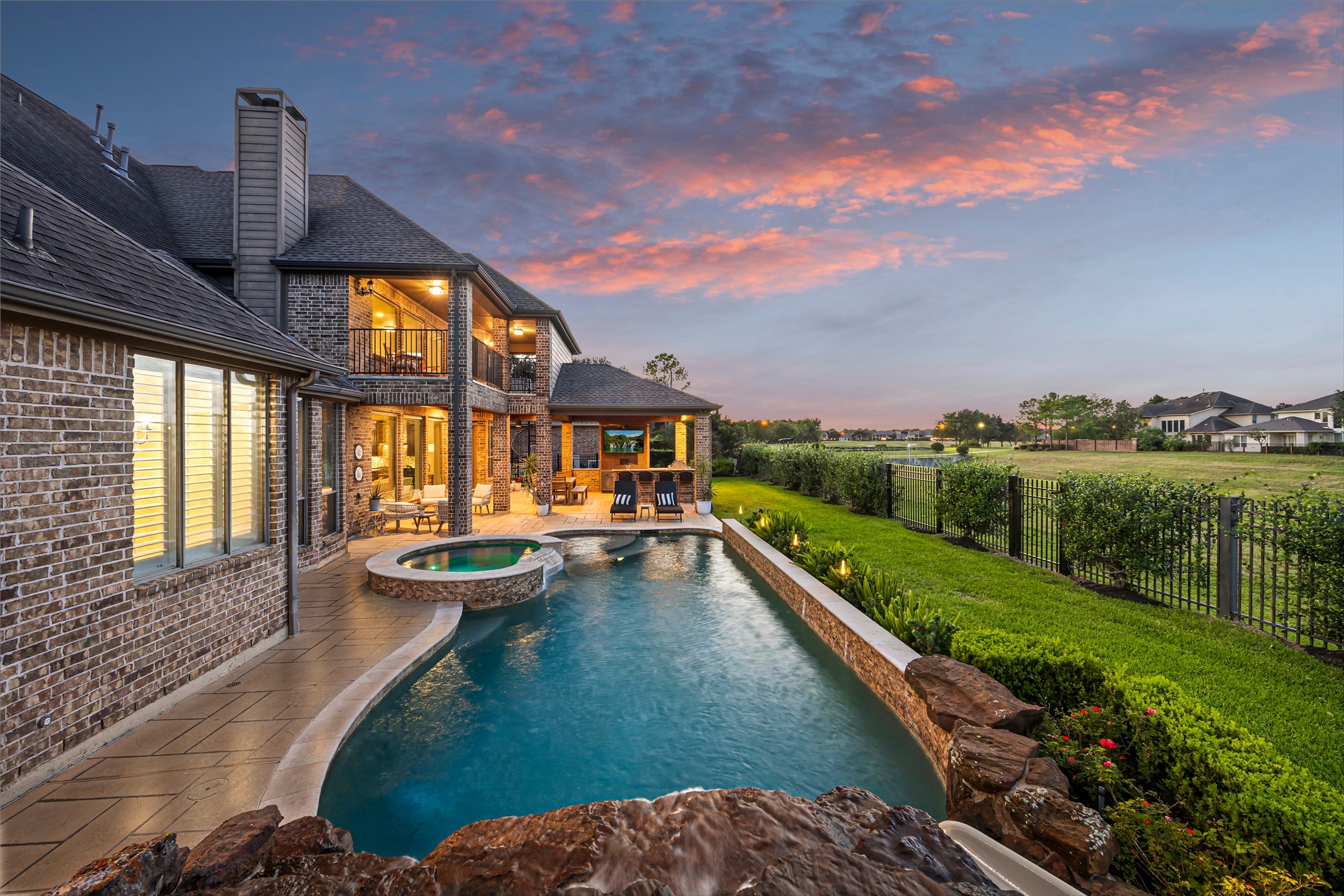 Rear elevation with illuminated pool and spa at dusk. Heated PebbleTec chlorine pool.
