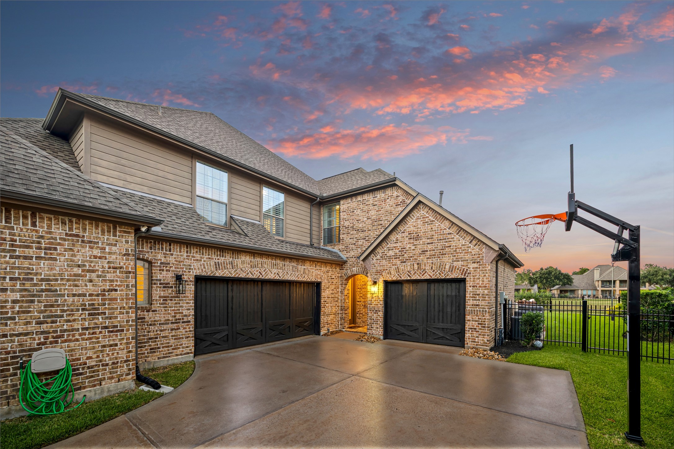 Attached three car garage with wide driveway and refined brick and stone detailing. New windows (2024). (Virtually enhanced: driveway reflection)