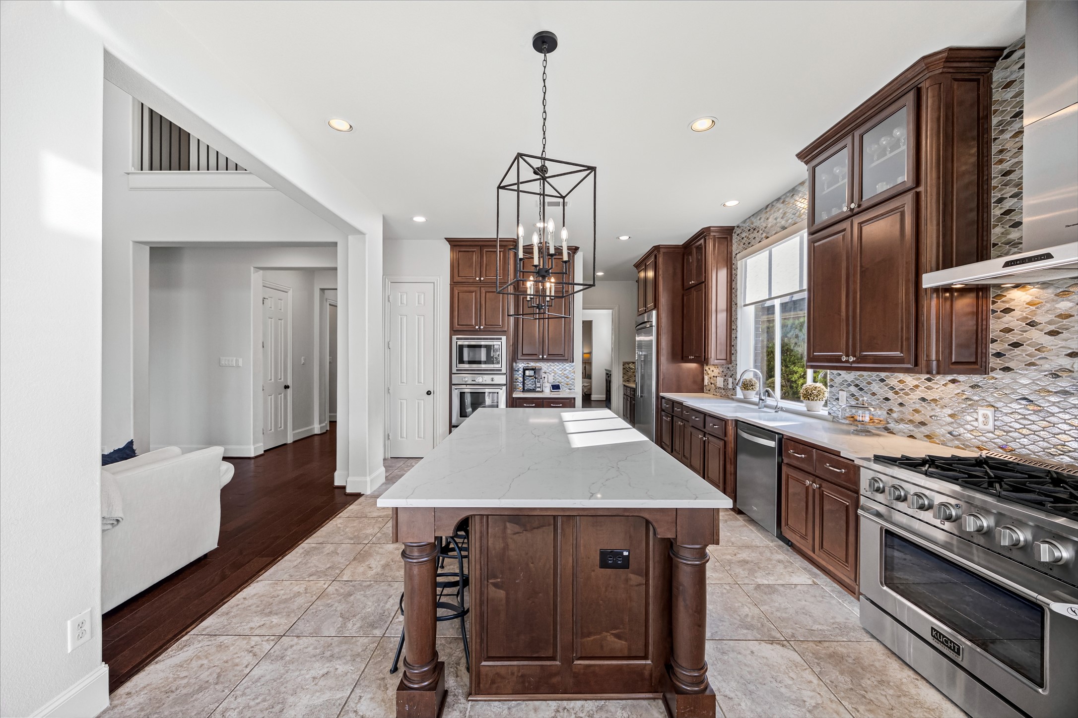 Gourmet kitchen with oversized island, designer pendant lighting, and rich dark wood cabinetry. New quartz countertops and backsplash (2024). Built-in Thermador fridge.