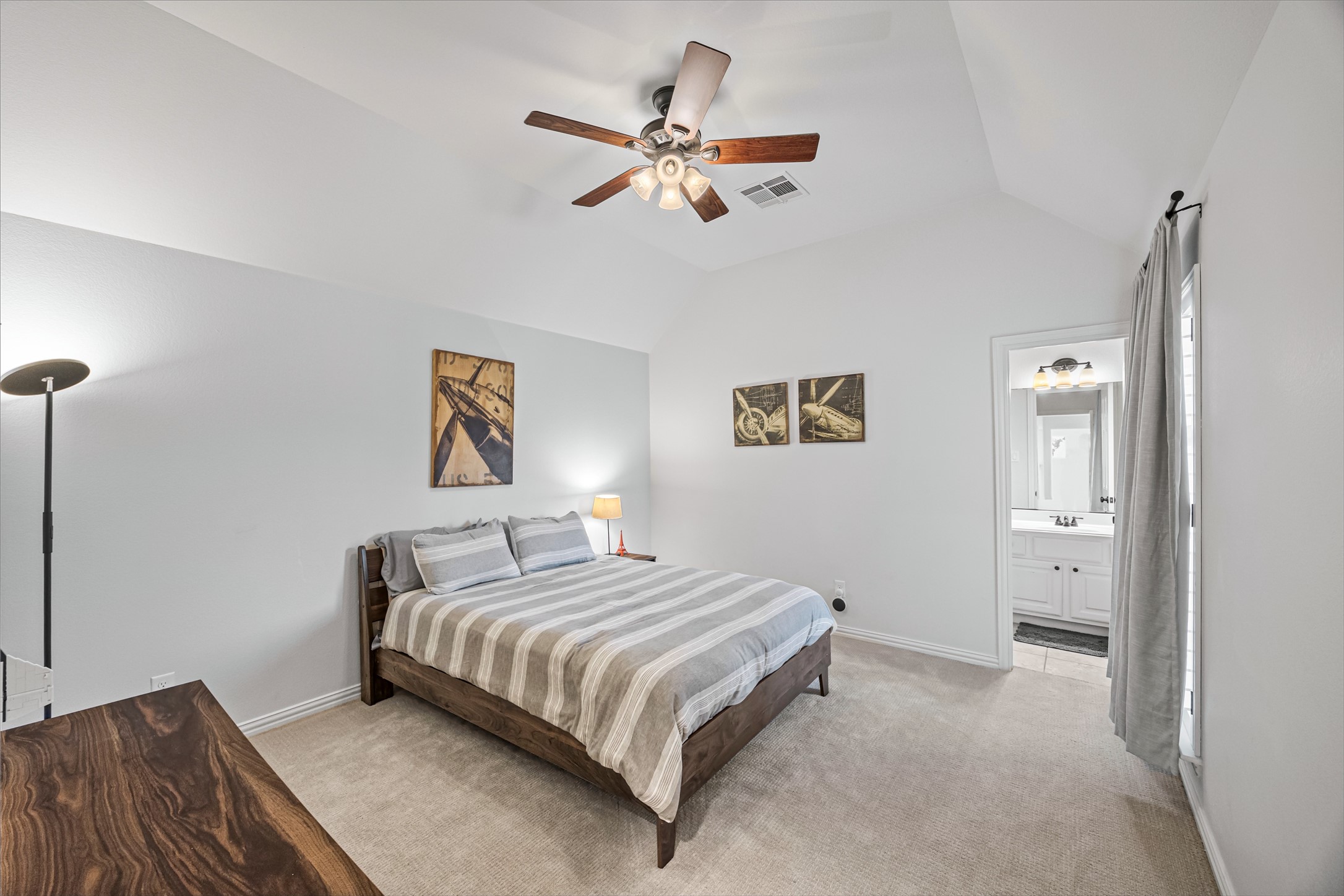 Bright bedroom with ceiling fan, large windows, and plush carpet.