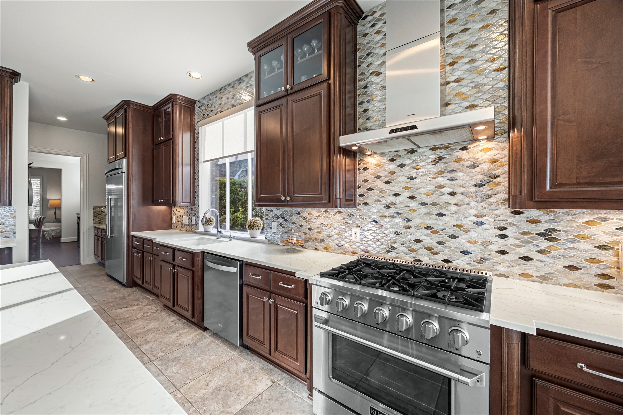 Chef's kitchen with mosaic tile backsplash, professional-style stainless steel range, and dark wood cabinetry. New luxury Kucht professional stove and oven (2024). New quartz countertops and backsplash (2024).