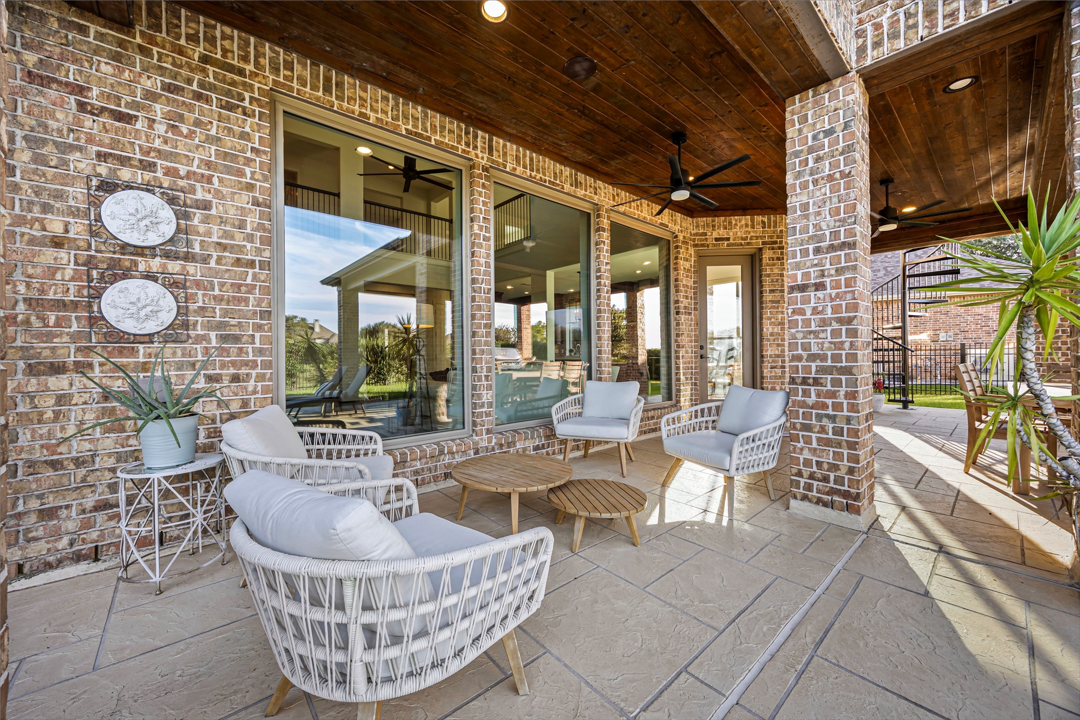 Covered patio lounge with stone accents and seating area overlooking the grounds. Exterior surround sound and ceiling fans.