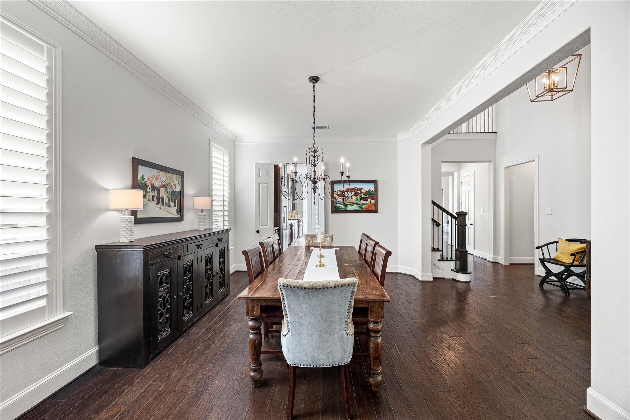 Formal dining room with designer chandelier, plantation shutters, and room for gatherings of every size. New windows (2024). All new lighting on dimmers.