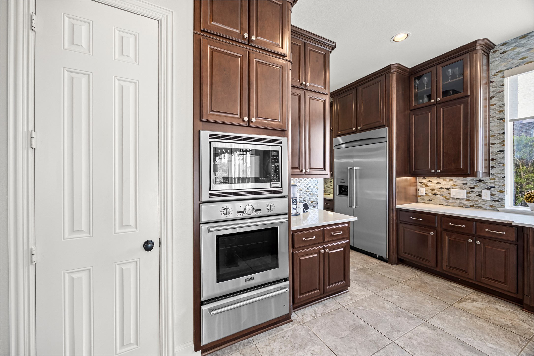 Kitchen featuring built-in wall oven and microwave, stainless steel appliances, and abundant cabinetry. Thermador oven, microwave, and warmer (electric). New quartz countertops and backsplash (2024).