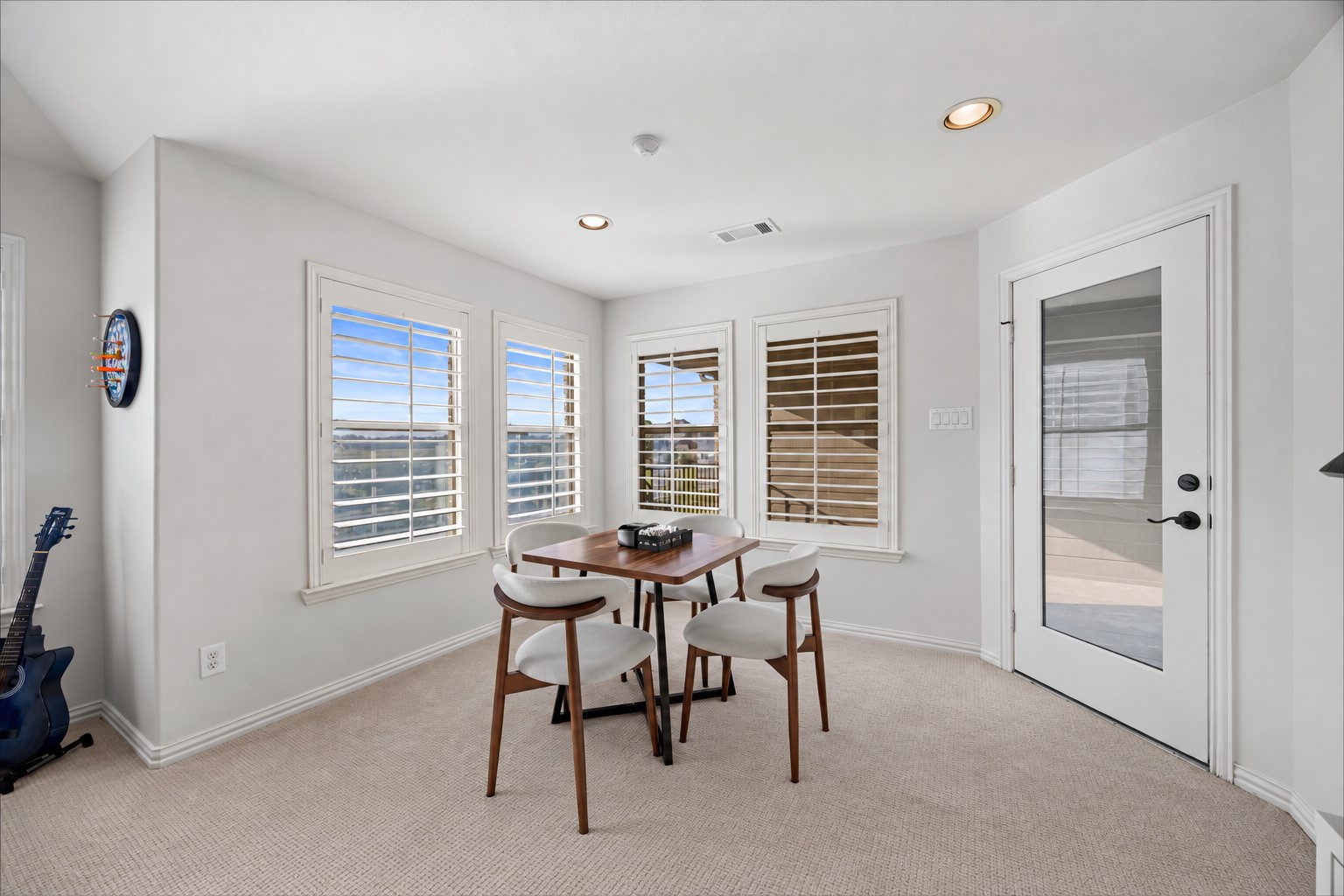 Versatile flex area with multiple windows, plantation shutters, and a glass door leading to the balcony.