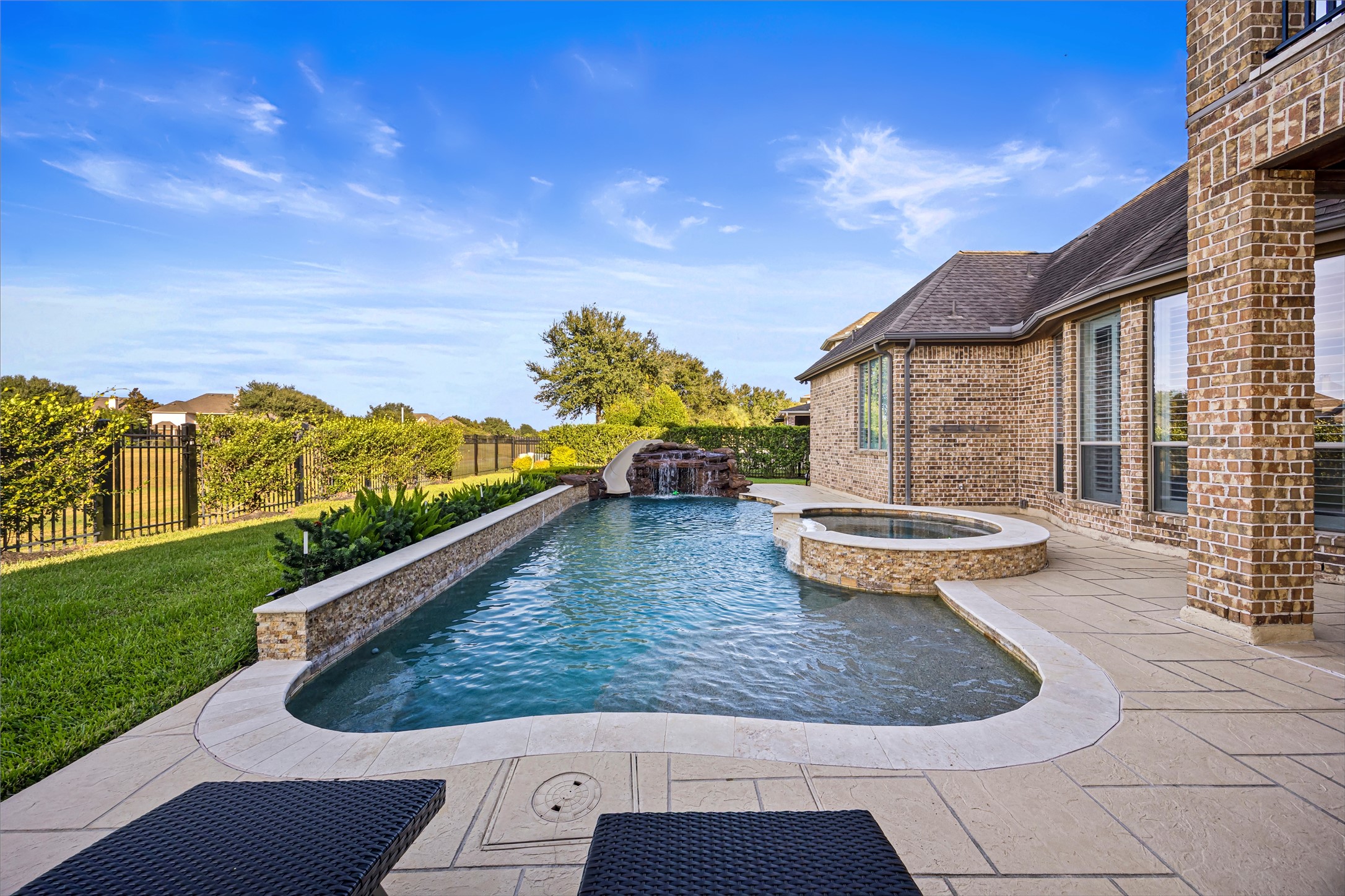 Resort-style pool and spa surrounded by expansive manicured lawn. Heated PebbleTec chlorine pool.