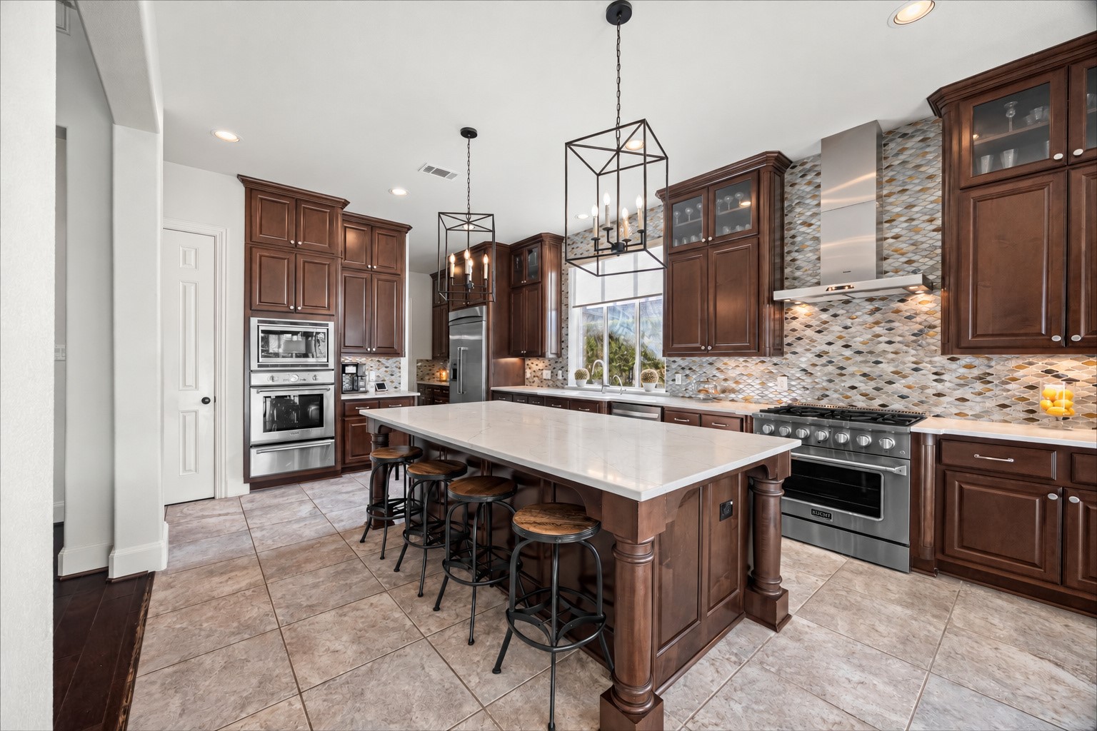 Gourmet kitchen with center island, pendant lighting, and extensive cabinet storage. New quartz countertops and backsplash (2024). Built-in Thermador fridge and large farm sink.