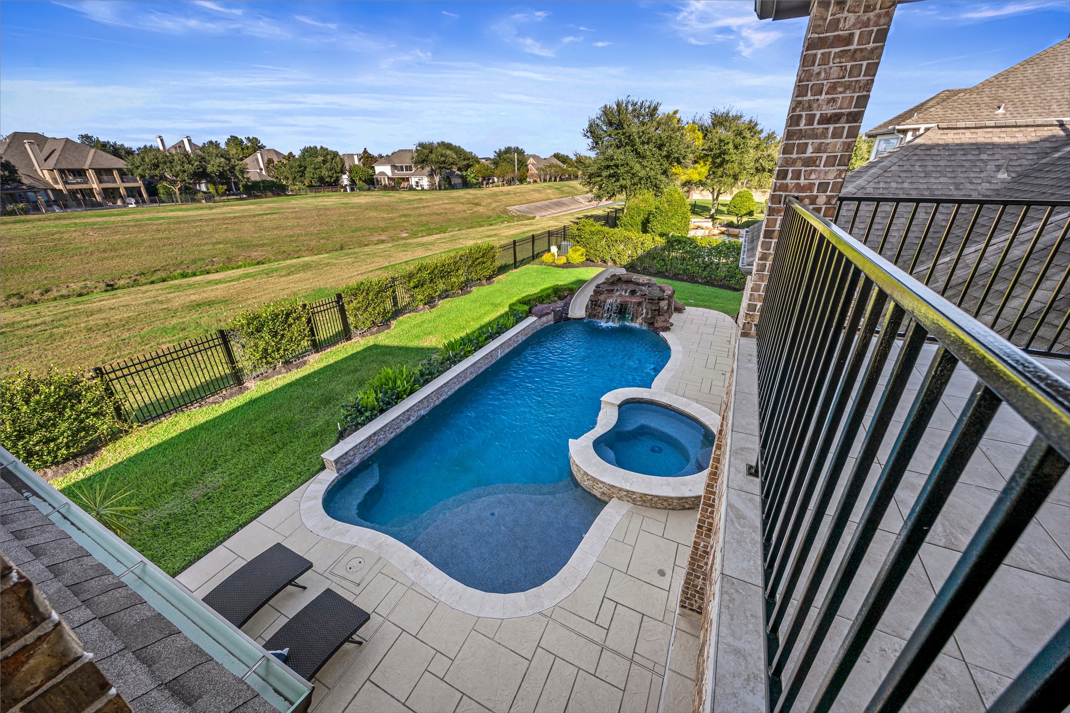 View from the upper balcony overlooking the pool, with no rear neighbors and a greenspace behind the home. Golf course views to the west.