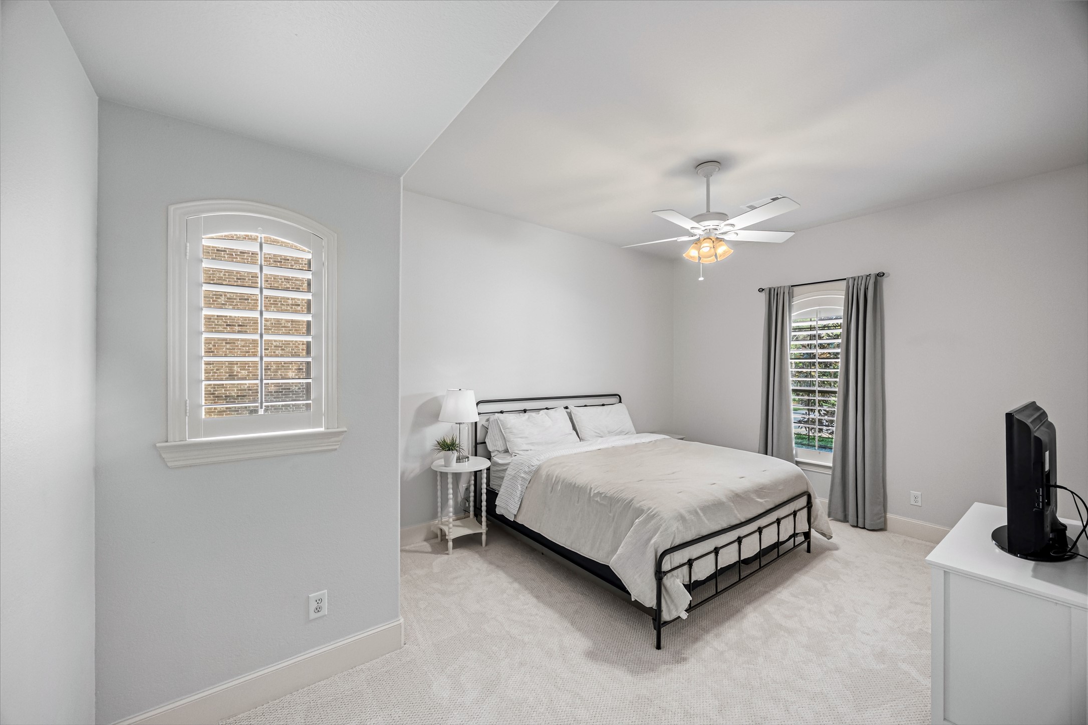 Serene bedroom with plantation shutters, ceiling fan, and plush carpet. New windows (2024). Updated paint throughout.