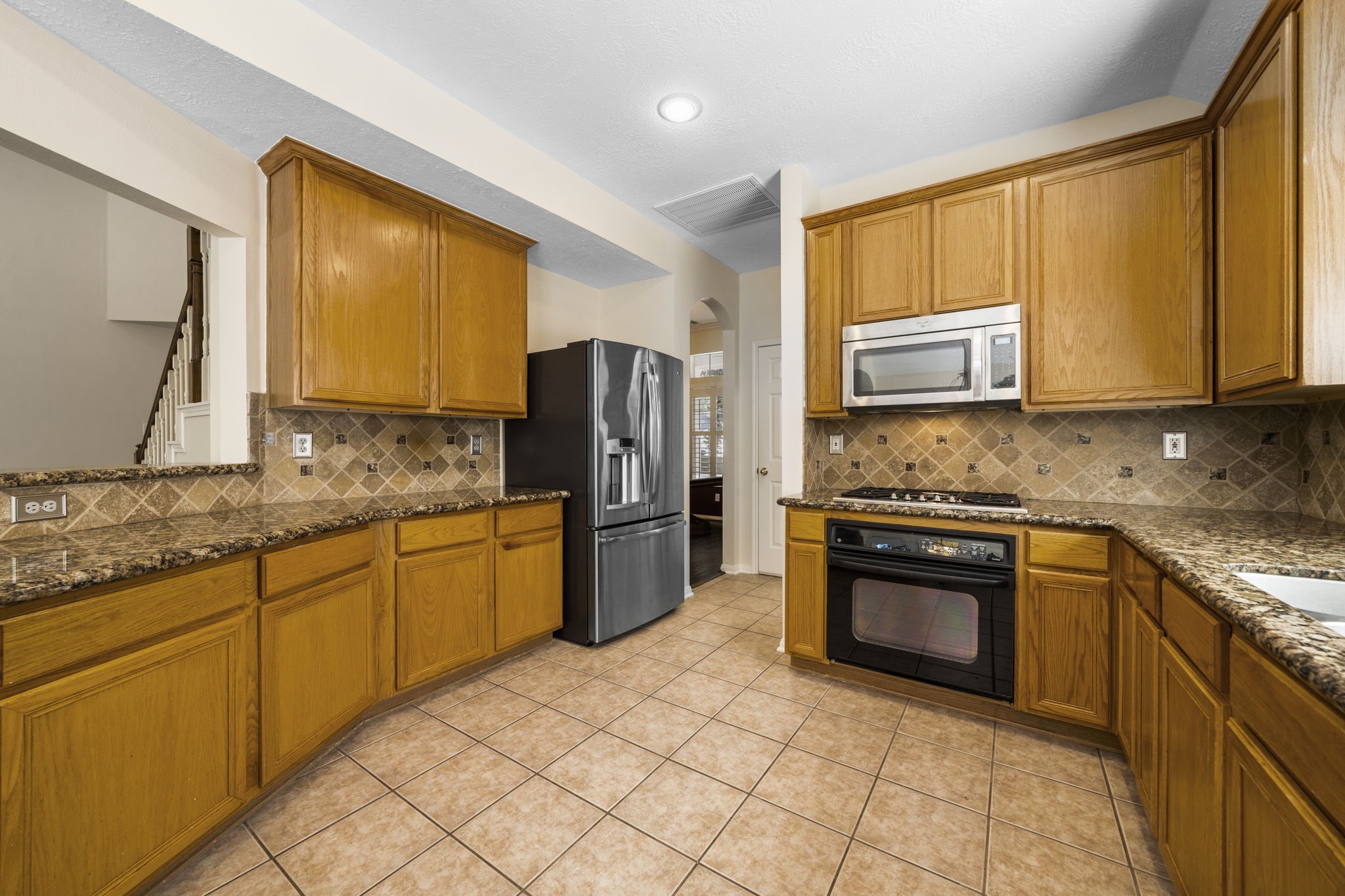 Spacious kitchen featuring charming wood cabinetry and granite countertops. Spacious kitchen featuring charming wood cabinetry and granite countertops.