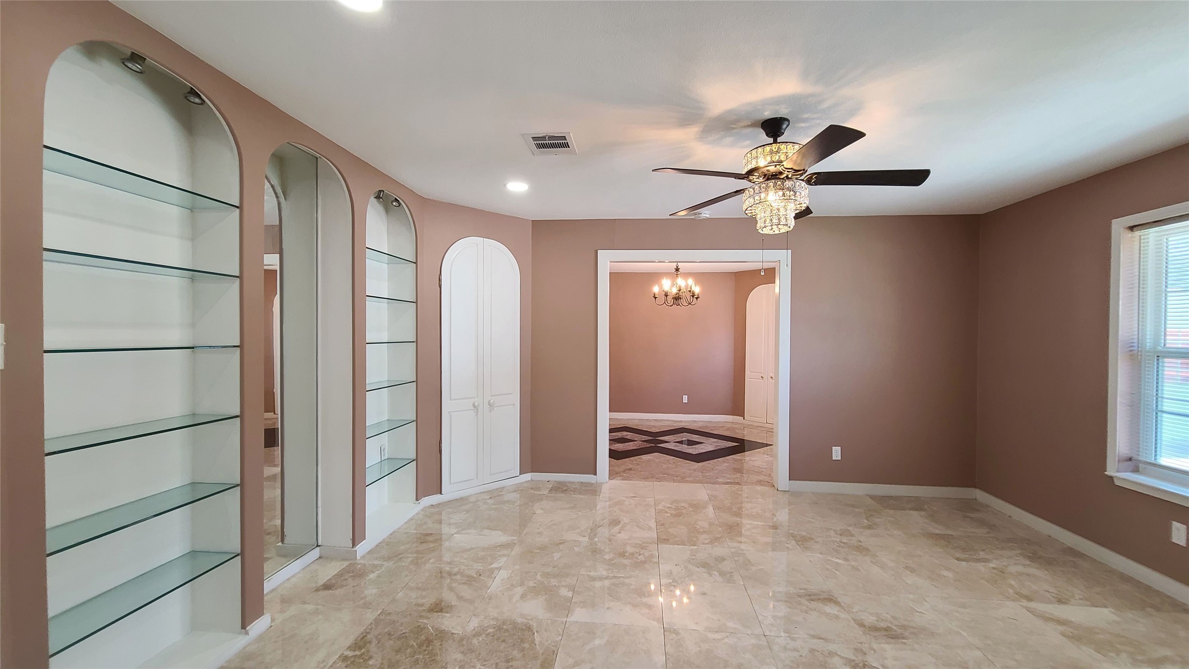 The formal living room boasts elegant fan lighting and two sleek glass shelves, creating a sophisticated ambiance.