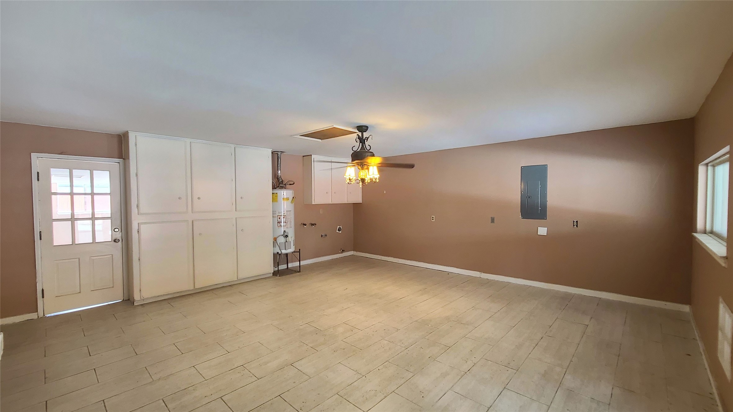 Spacious room with ample built-in cabinetry, a ceiling fan, and natural light, perfect for versatile use.