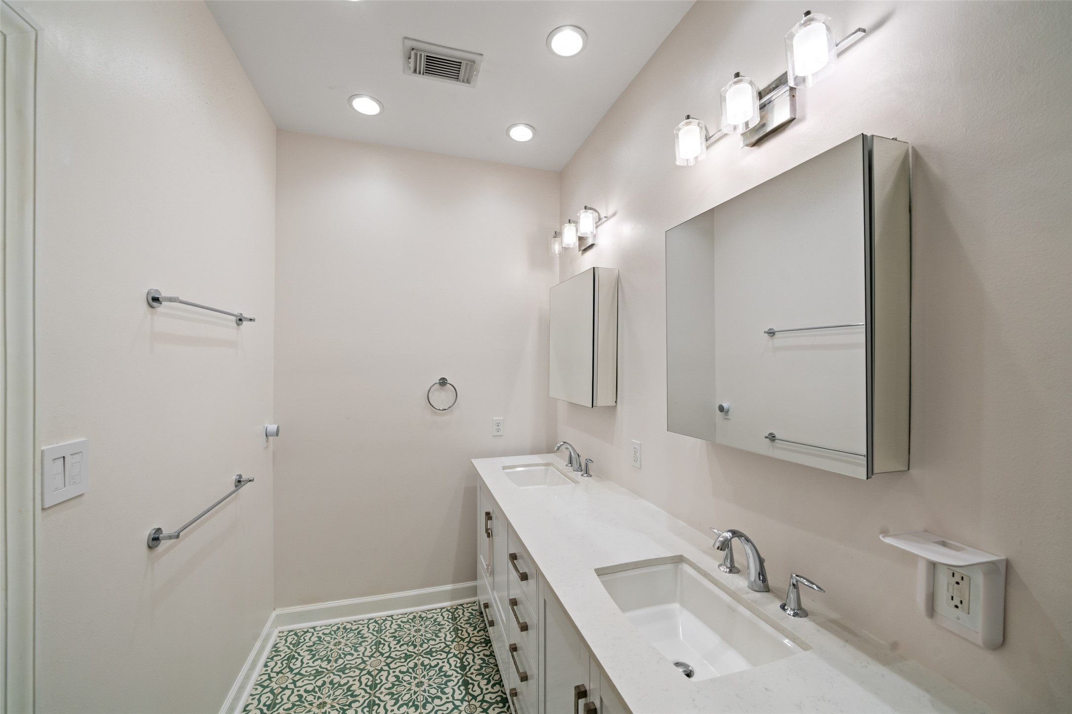 Primary en-suite bath featuring a double-sink vanity, ample storage, and mosaic tile flooring.