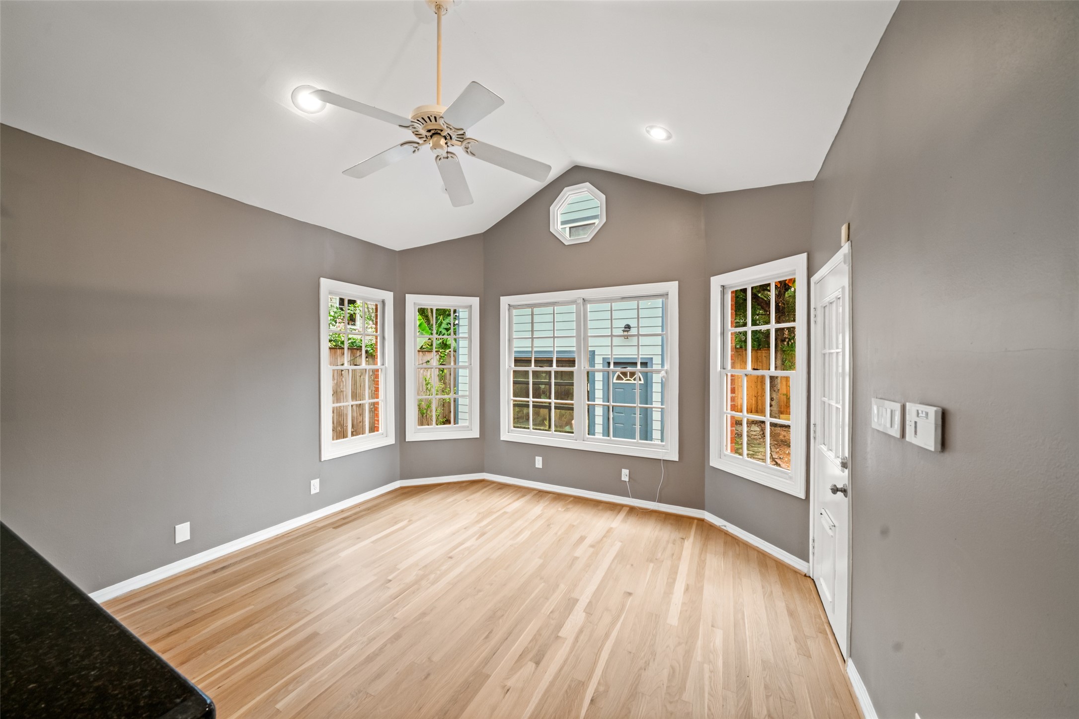 Breakfast room featuring a vaulted ceiling, wood floors, and windows overlooking backyard.
