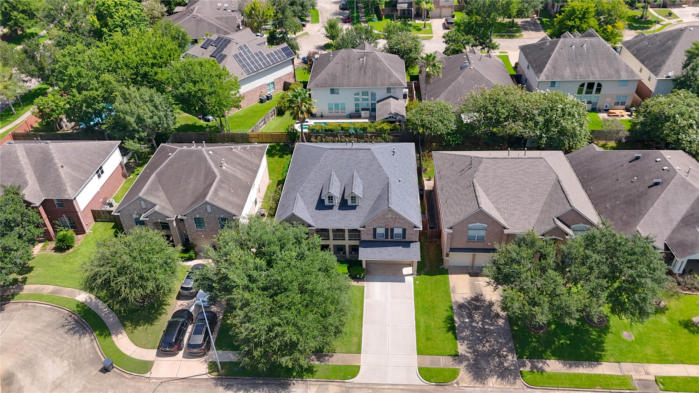 Beautiful two-story home nestled in a tree-lined suburban neighborhood, featuring a spacious driveway and lush green lawn.