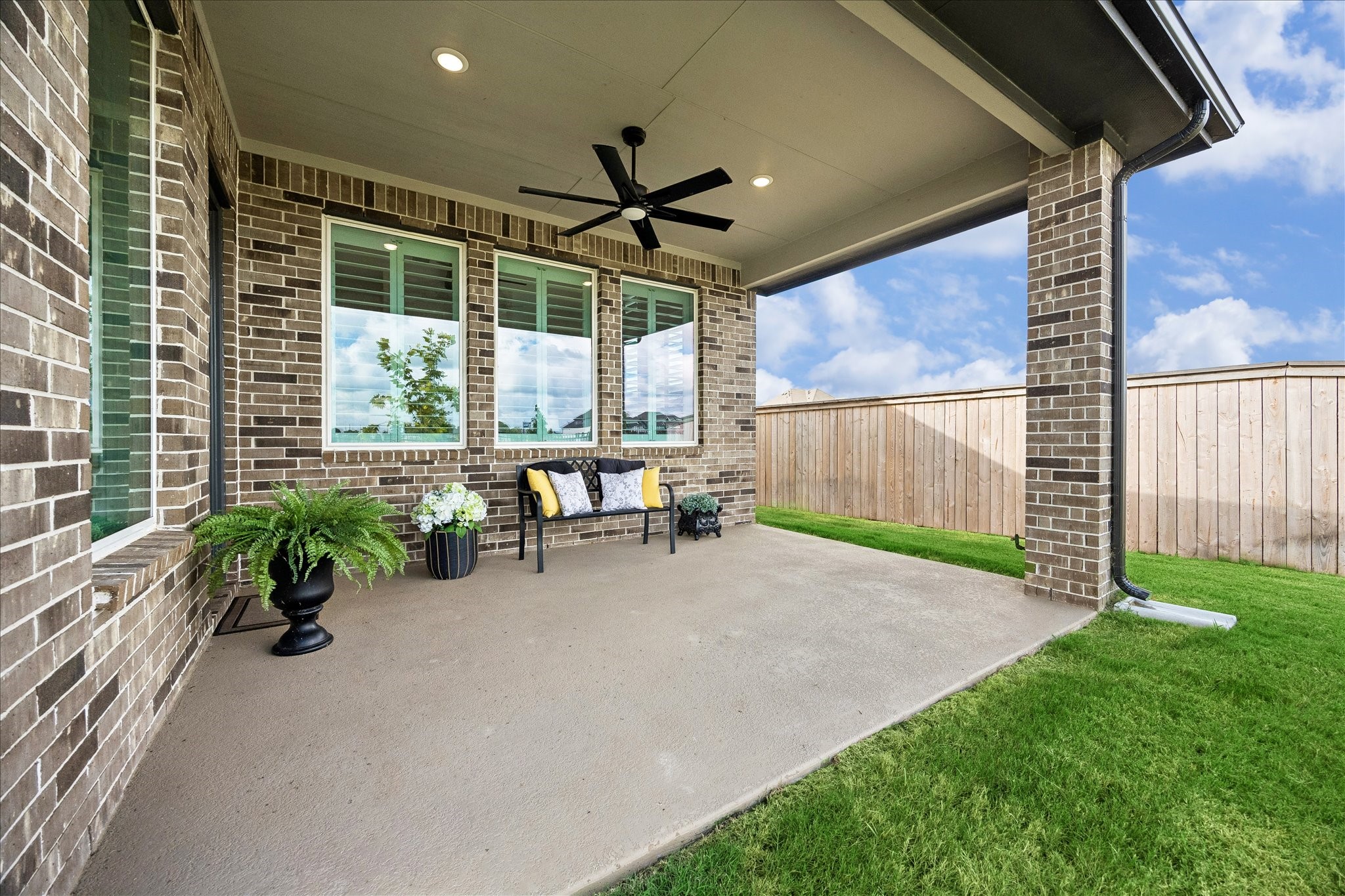 This covered patio expands your living space, featuring recessed lighting, a ceiling fan, and stylish brick accents. Enjoy seamless indoor-outdoor living through a wall of windows, with a gas hook-up ready for your dream outdoor kitchen. The patio overlooks the backyard, offering peaceful views of the water and trails.