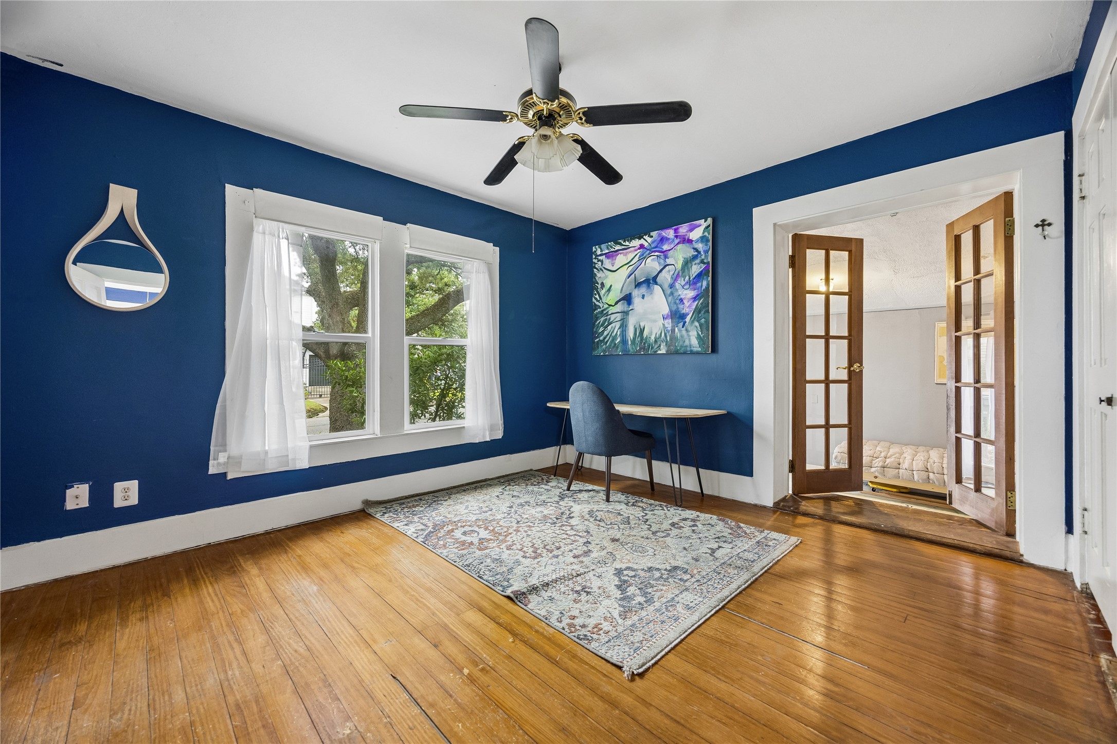 Rich blue walls and warm wood floors give this light-filled room plenty of personality, while French doors provide a graceful transition into the adjoining space.