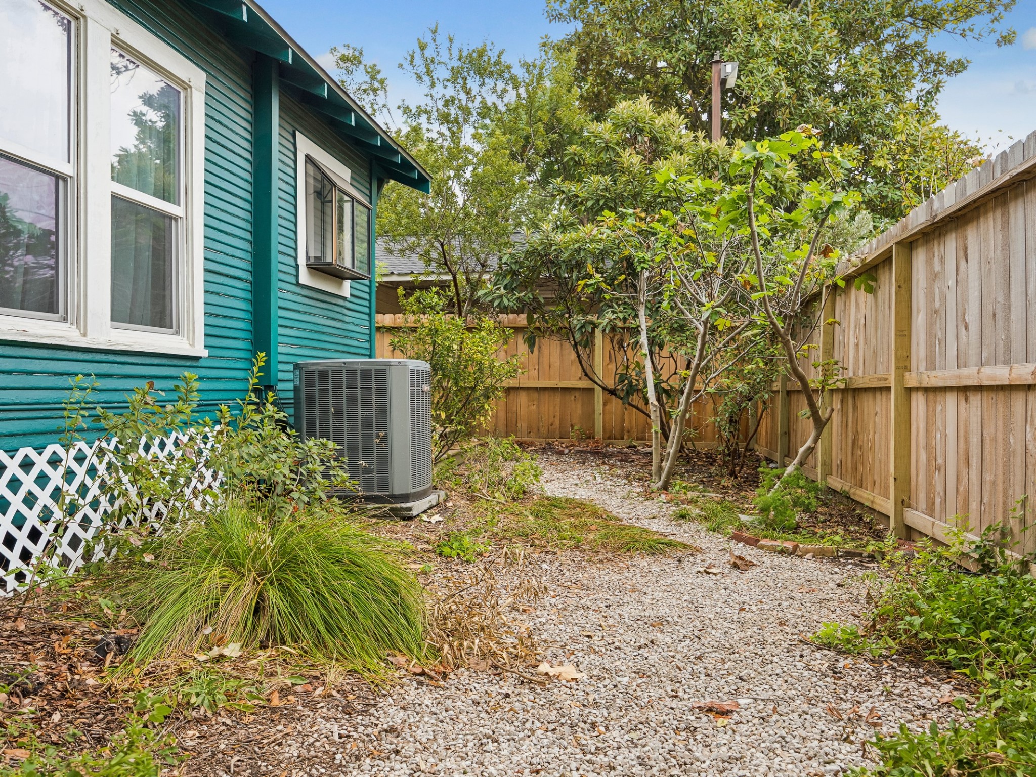 A fenced side yard with a winding gravel path and established plantings adds another charming outdoor dimension to the property.
