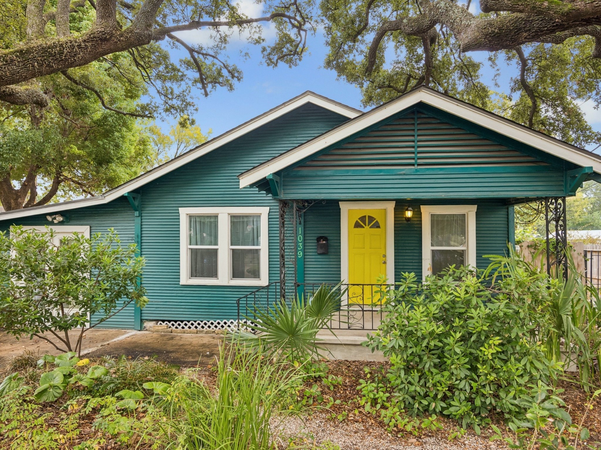 Nestled beneath a canopy of beautiful, mature trees, this character-filled home makes a memorable first impression with its colorful exterior and welcoming covered entry.