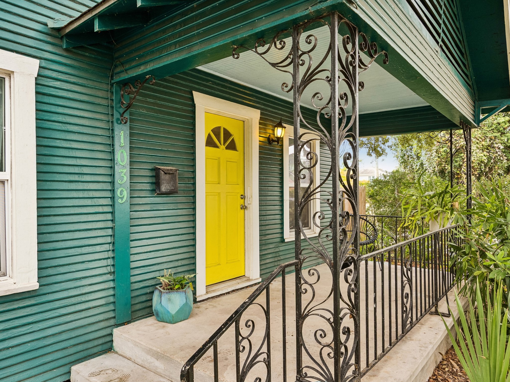 The covered front porch welcomes you home with an eye-catching yellow door and decorative ironwork, setting the tone for the home's distinctive character
