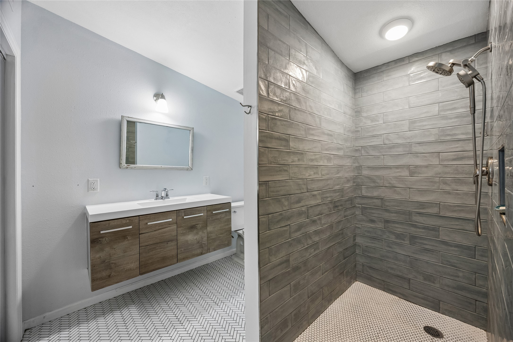 This striking bath pairs a floating double vanity and patterned flooring with a spacious tiled walk-in shower for a clean, contemporary look