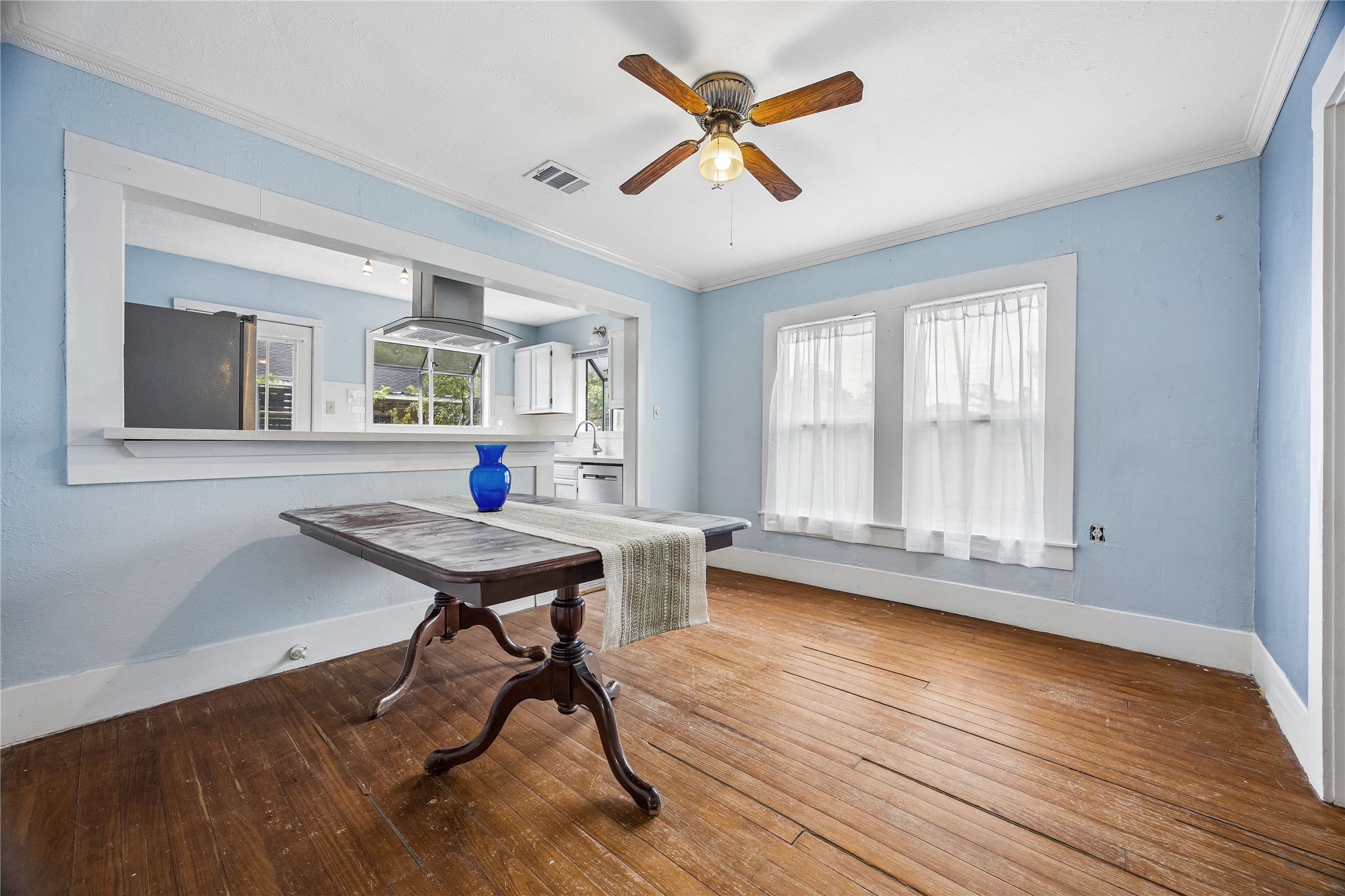 This cheerful dining area features wood floors and plentiful natural light, plus a wide pass-through to the kitchen that keeps the spaces comfortably connected.
