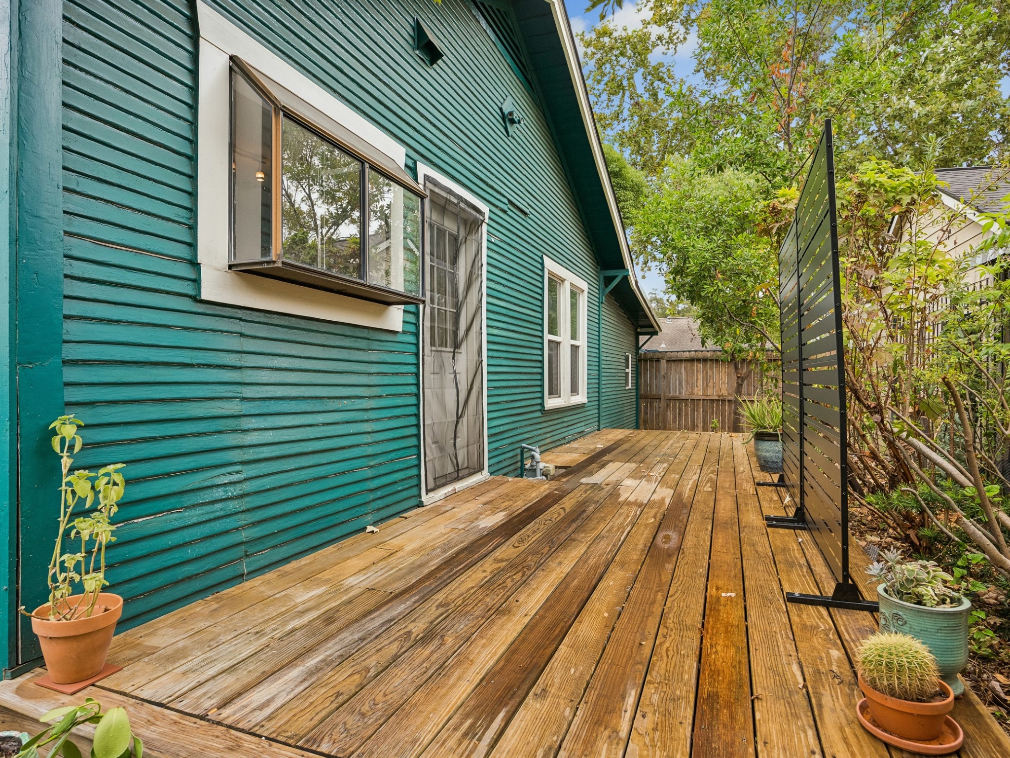 Step outside to a private-feeling wooden deck surrounded by greenery, offering an inviting spot for morning coffee, container gardening, or relaxed outdoor lounging