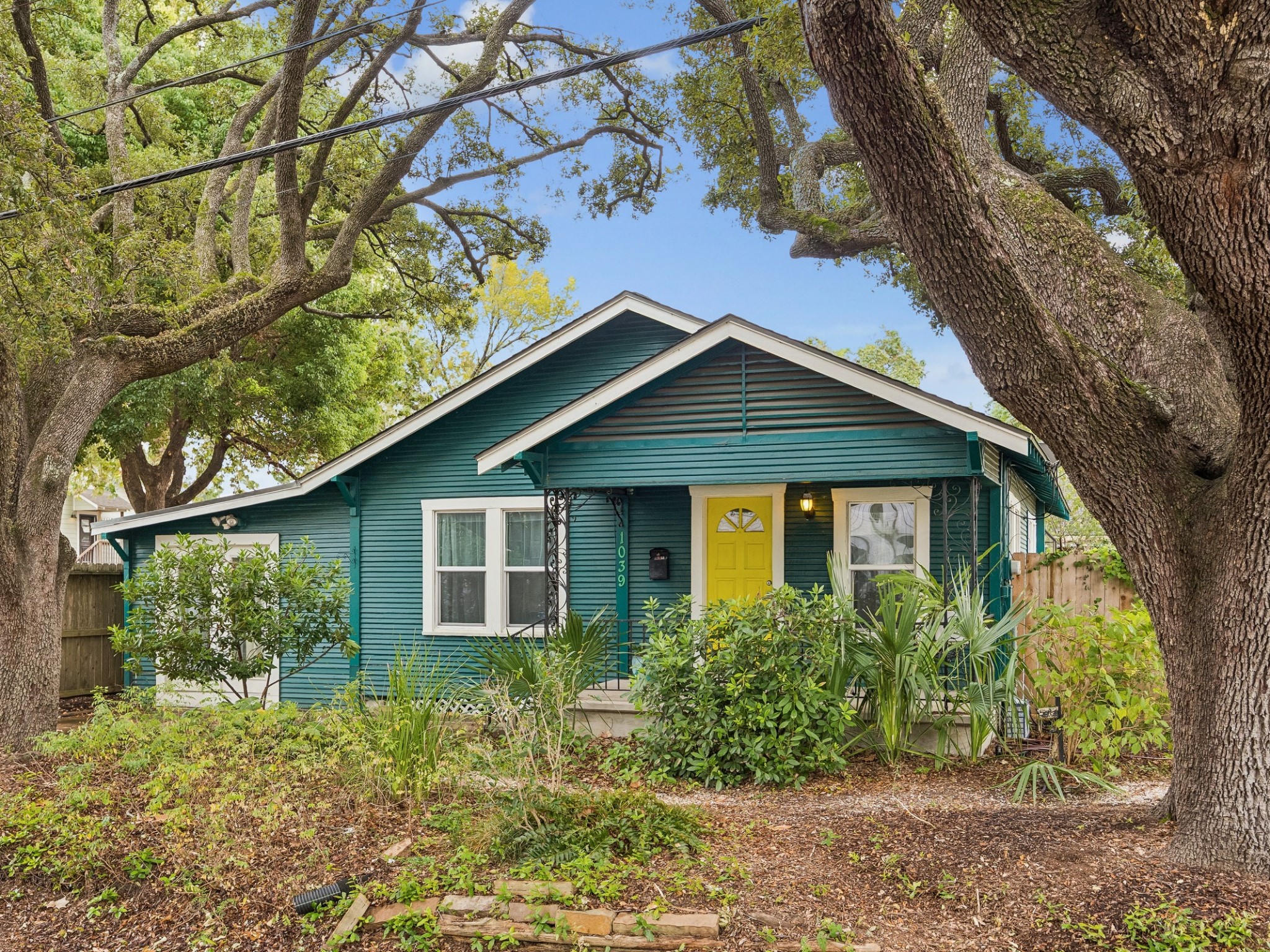 A charming bungalow exterior framed by mature trees and lush landscaping.