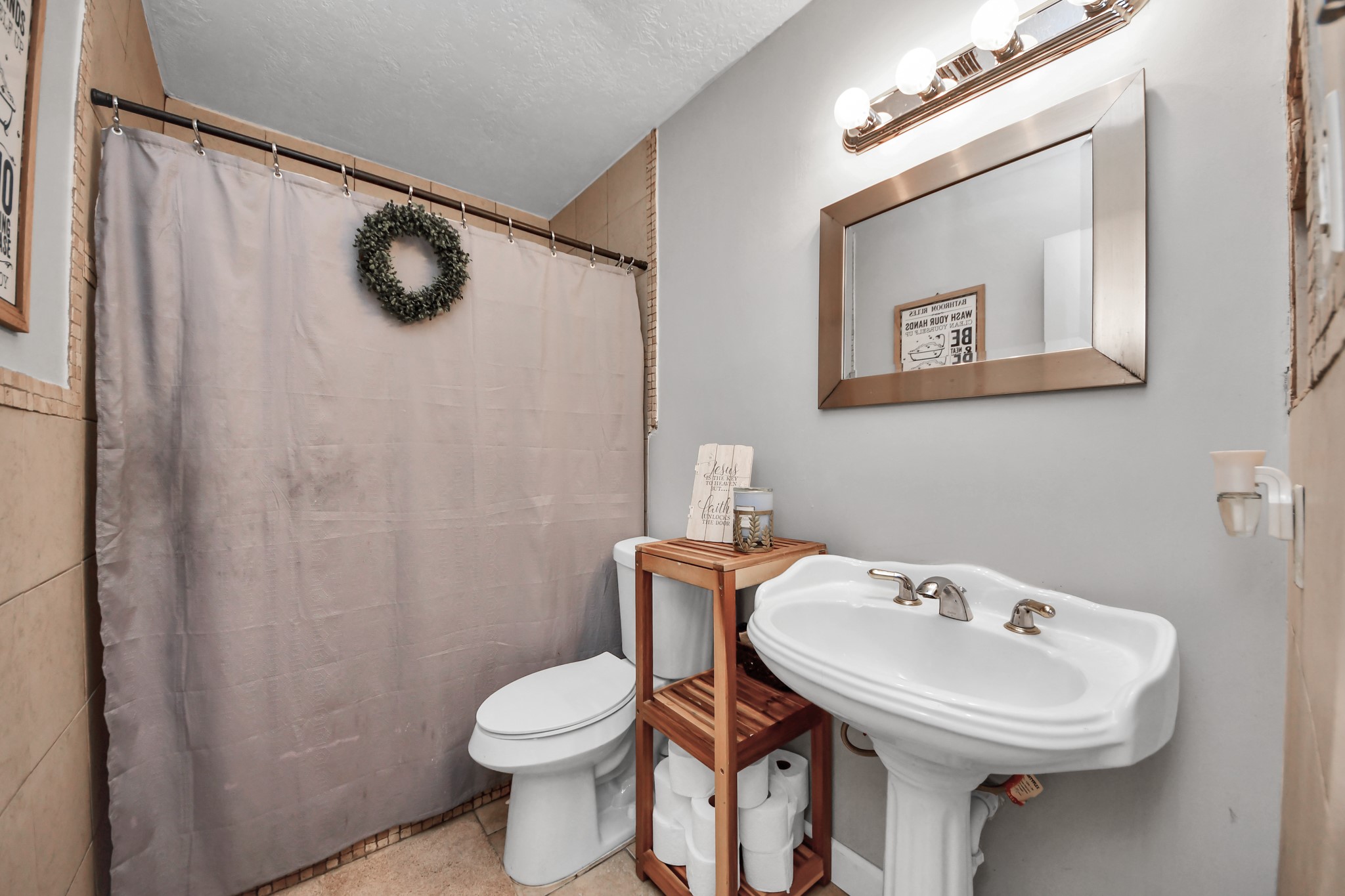 Spacious secondary bathroom featuring a tiled walk-in shower, pedestal sink, and a neutral color palette. A functional layout with charming details and room for everyday convenience.